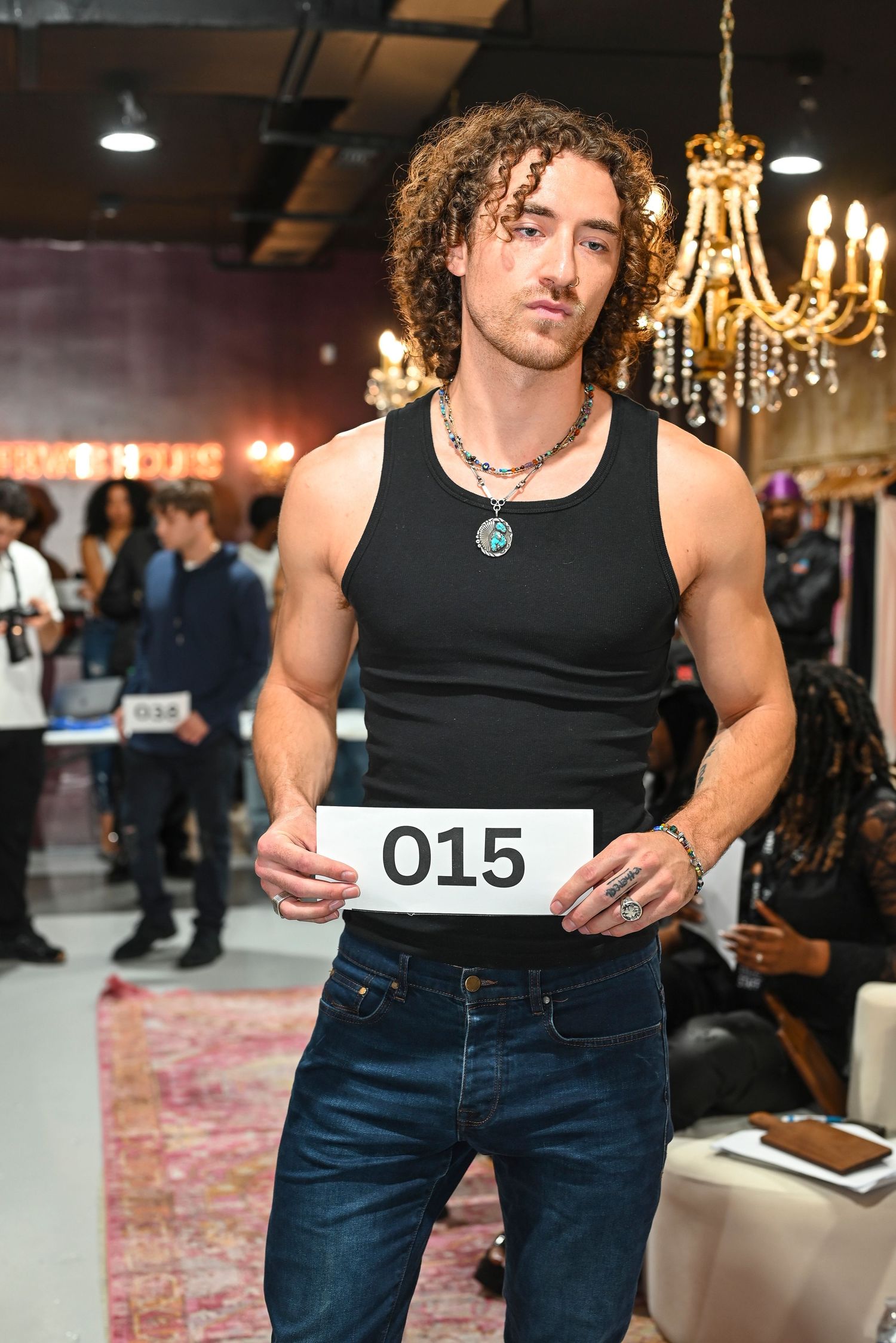 Runway models wearing black tank tops and dark denim during a fashion show.