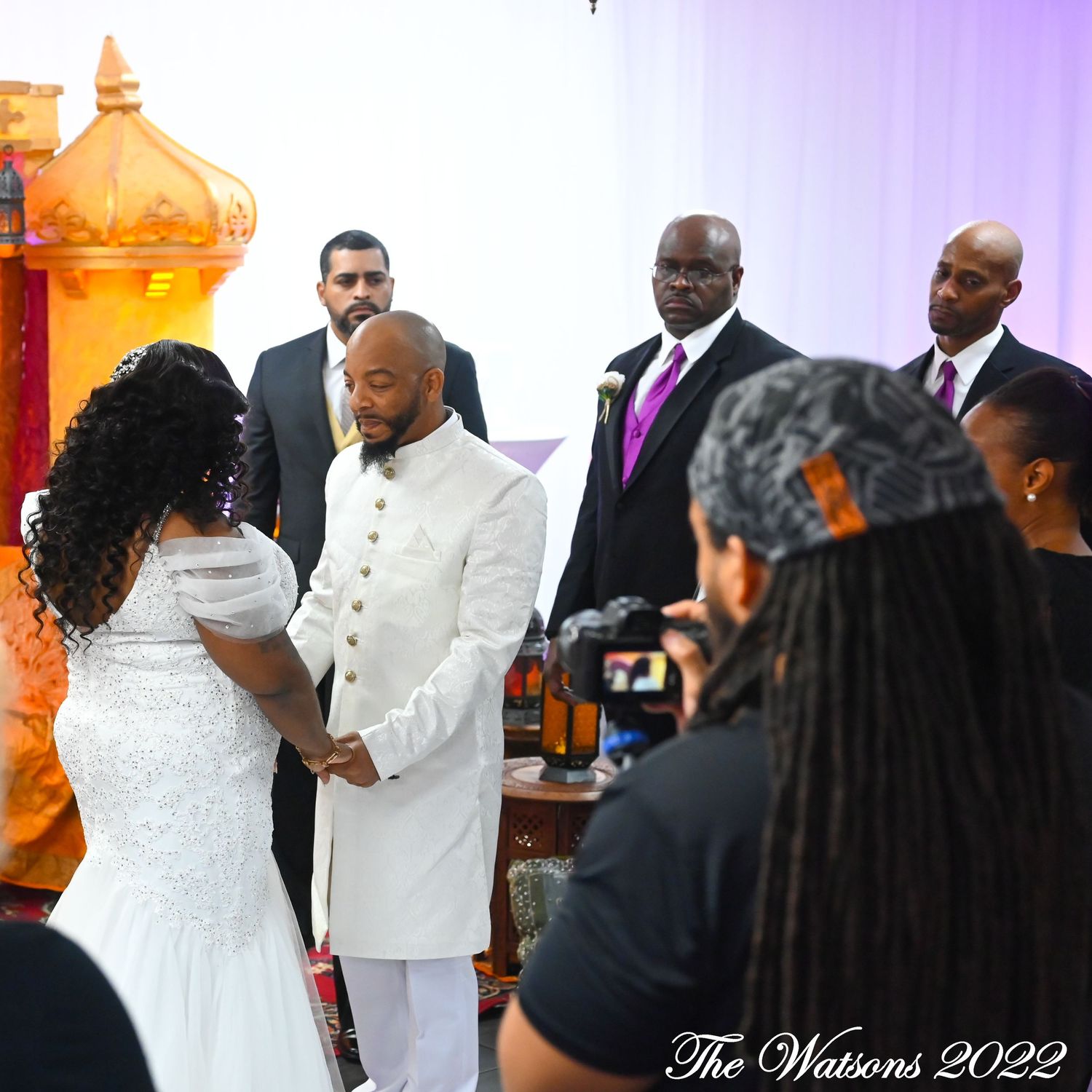 Bride and groom exchange vows at wedding ceremony with groomsmen standing behind them in 2022.