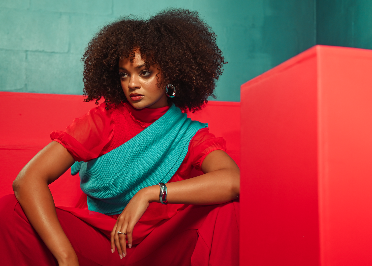 Fashion shoot against vibrant red and turquoise walls with dramatic poses.
