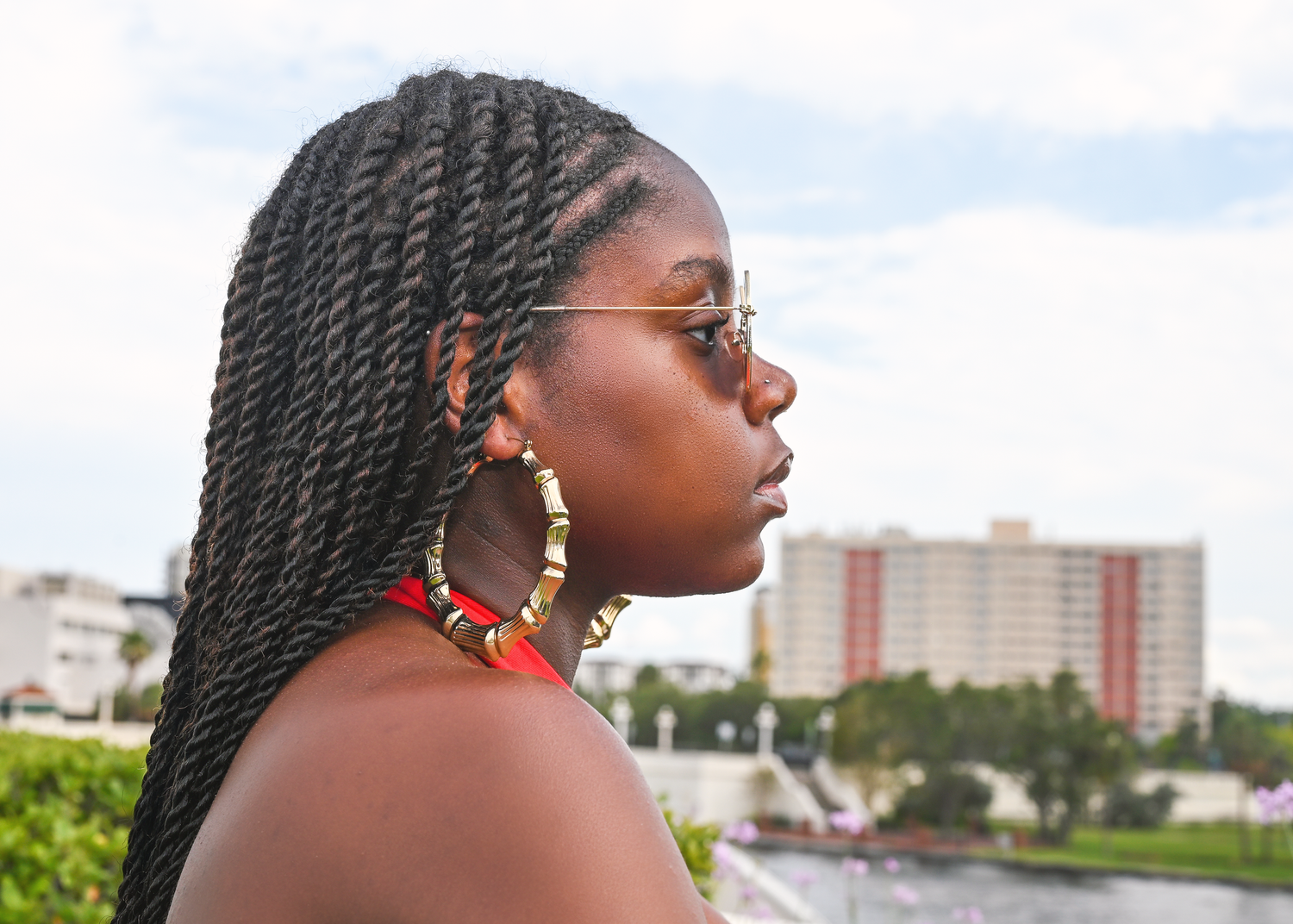 Artistic outdoor portrait series with braided hair and statement earrings against a cityscape.