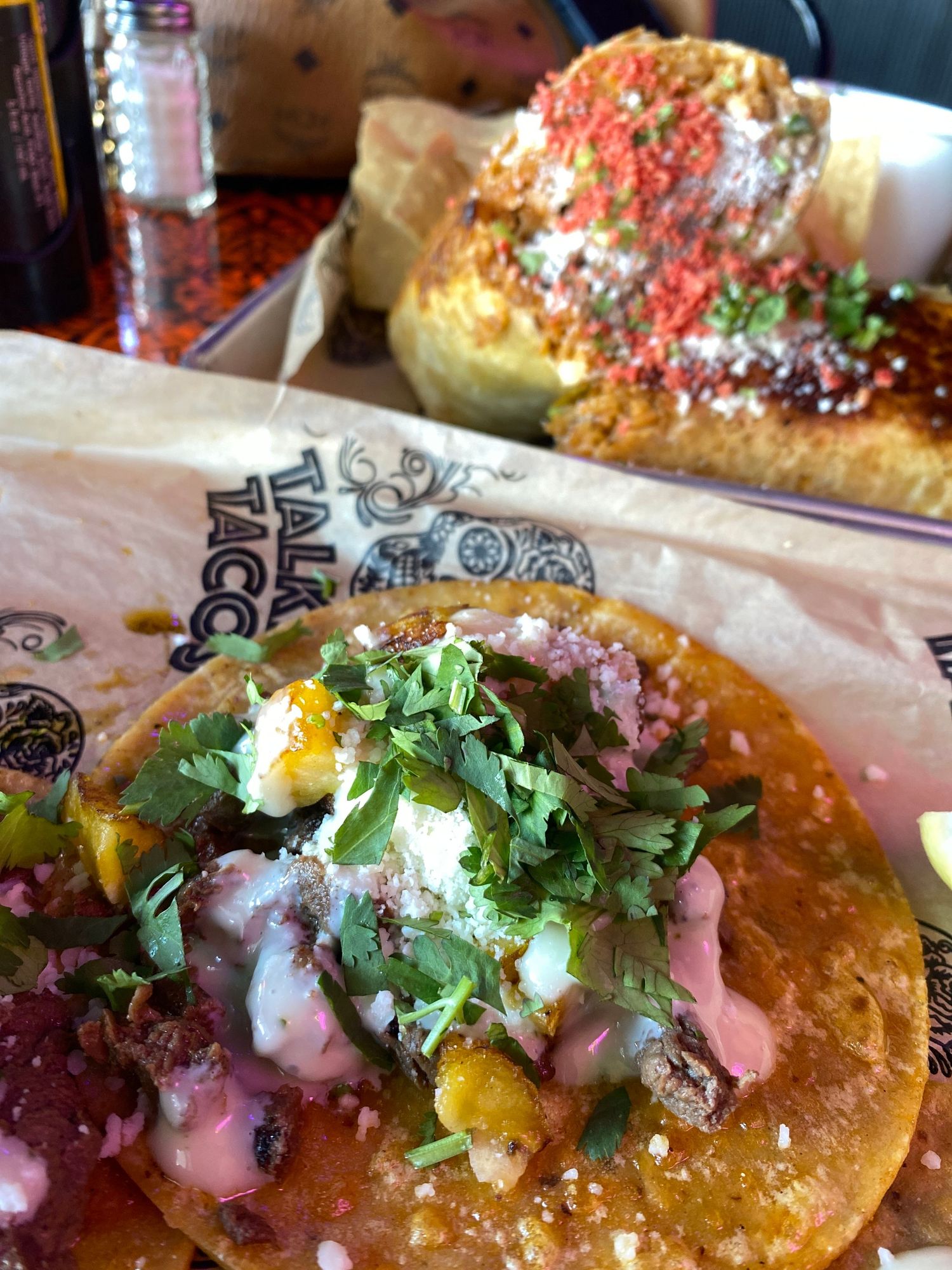 Mexican-style street tacos topped with fresh cilantro and sauce on a white plate.