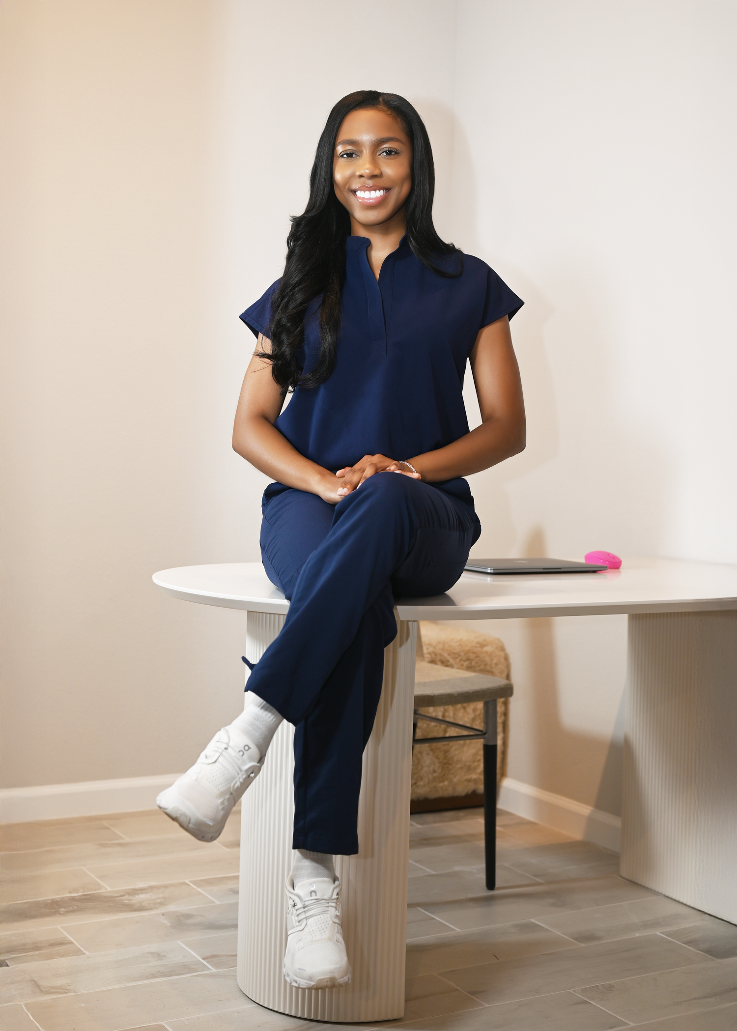 Modern business portraits on white furniture with navy outfit and white sneakers.