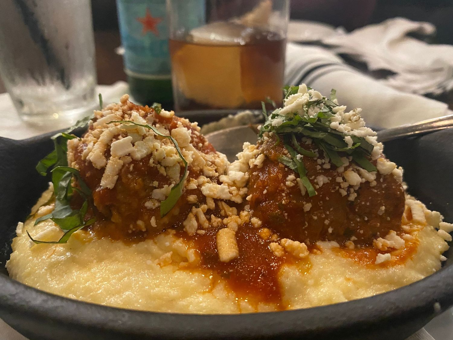 Meatballs served on creamy polenta with red sauce and crushed nuts.