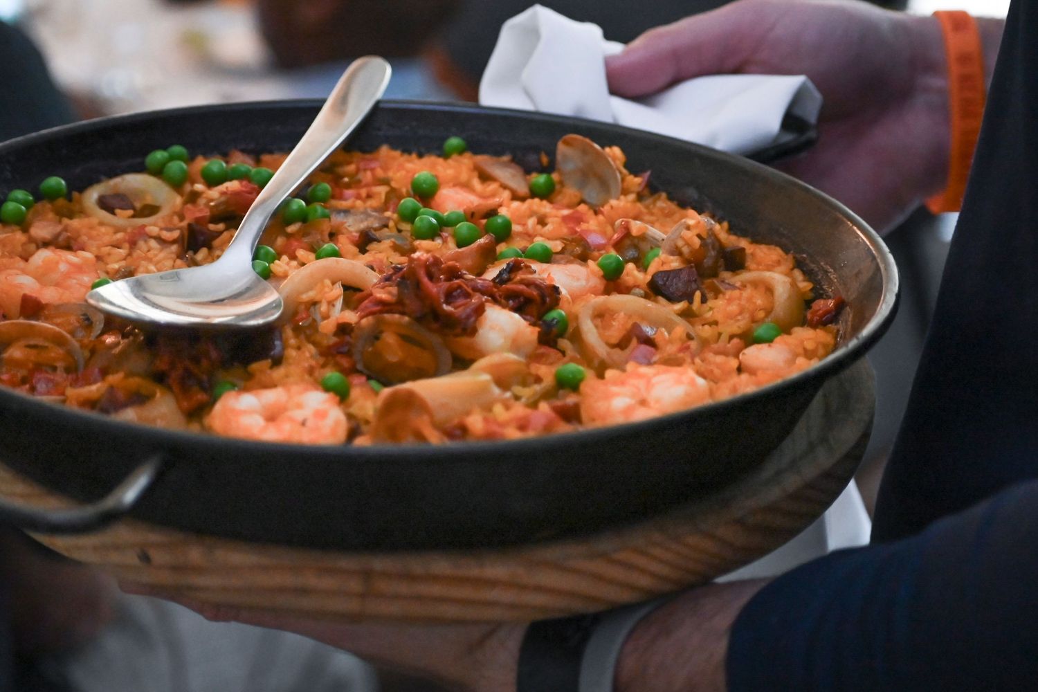 Delicious seafood paella dish with shrimp and rice cooking in a large black pan.