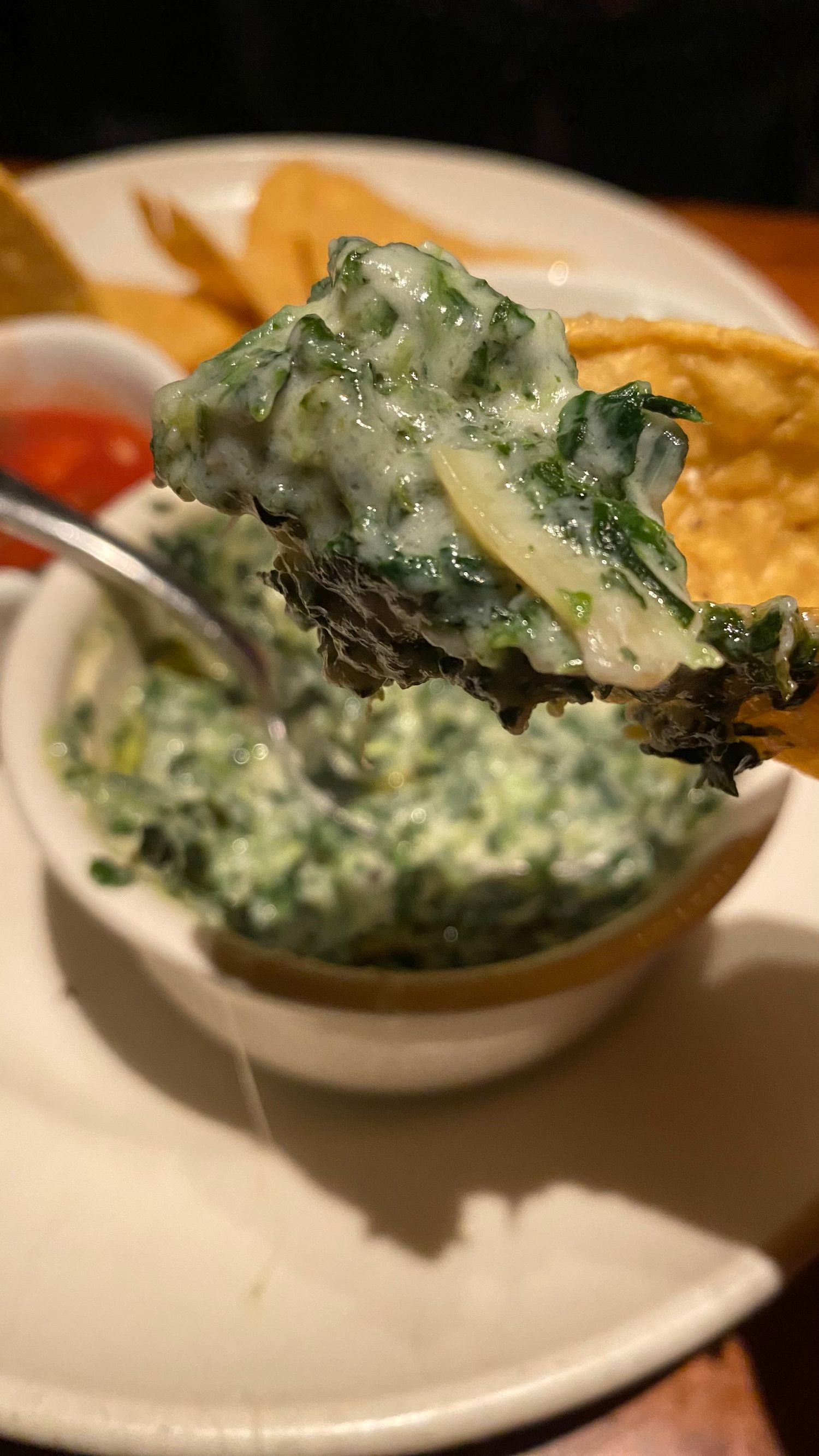 Creamy spinach dip with melted cheese served in a white bowl.
