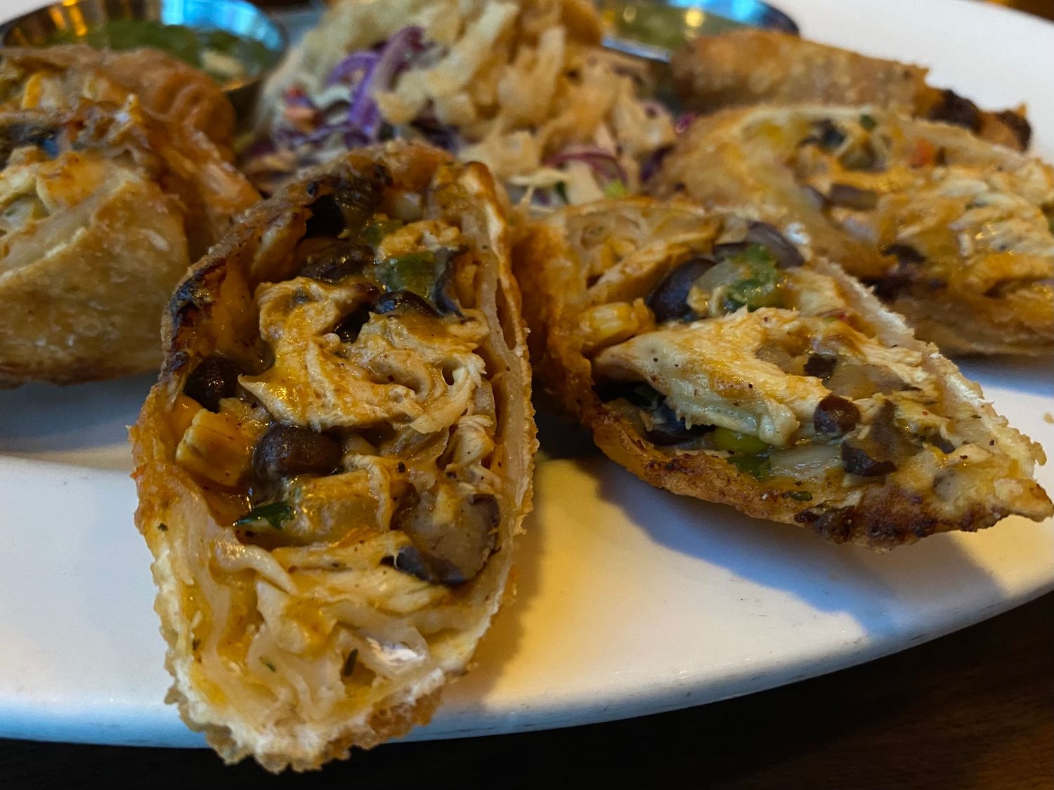 Grilled oysters topped with melted cheese and herbs on white plate.