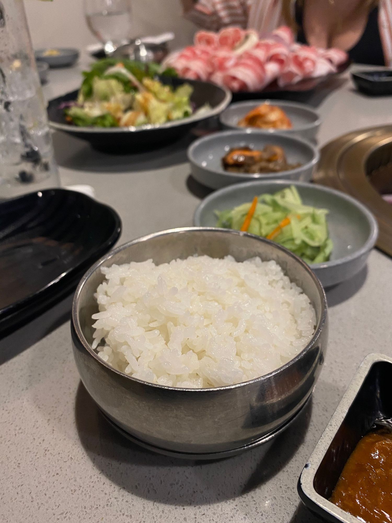 White steamed rice served in black bowls at a restaurant table setting.