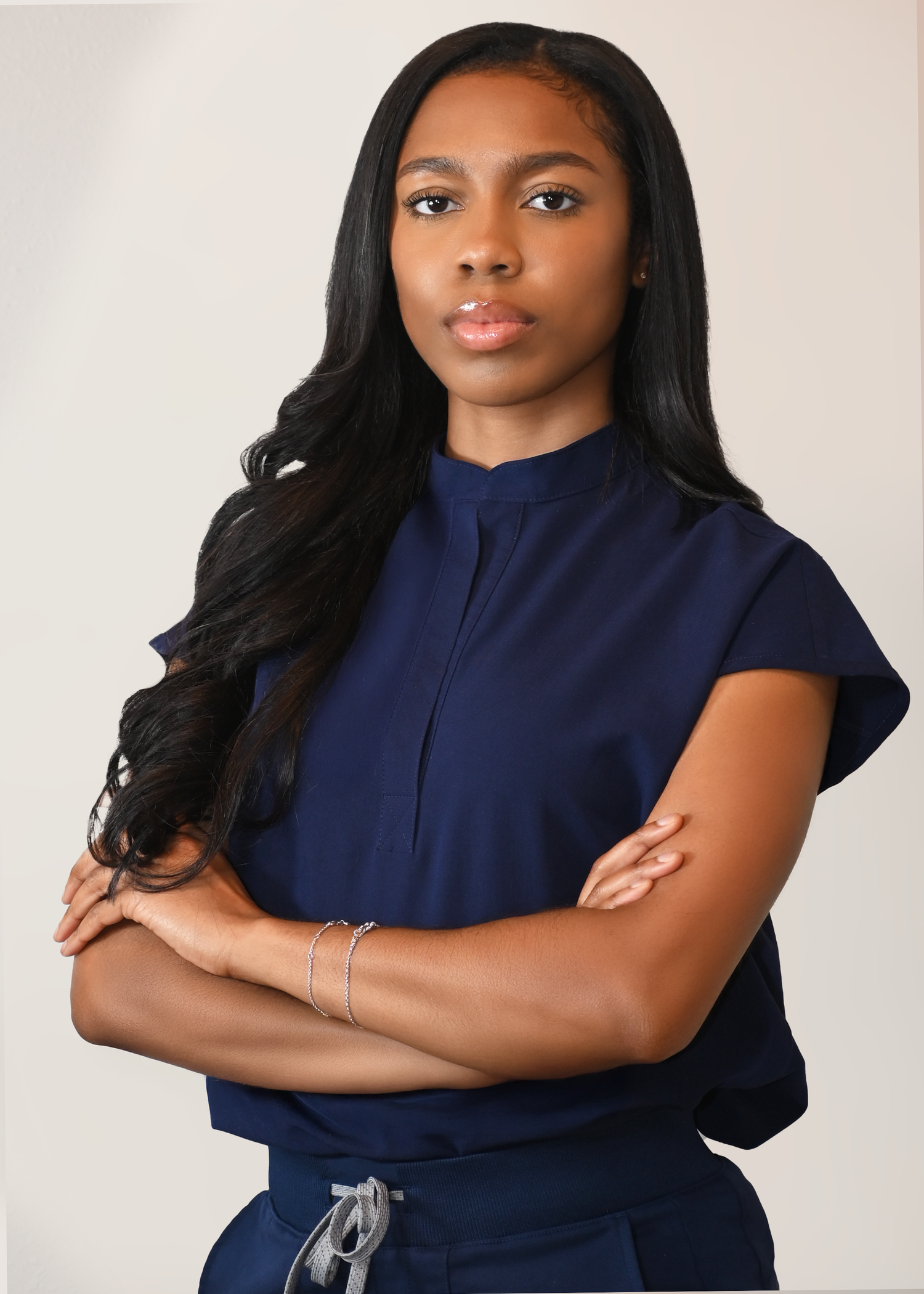 Professional studio portrait of someone in a navy blue top against a light background.