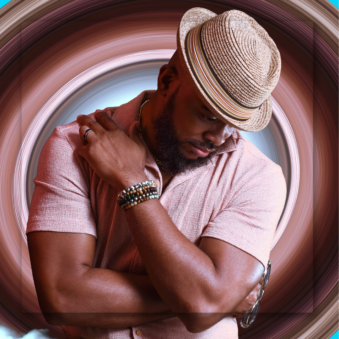 A person in a fedora and pink shirt poses thoughtfully in a circular frame.