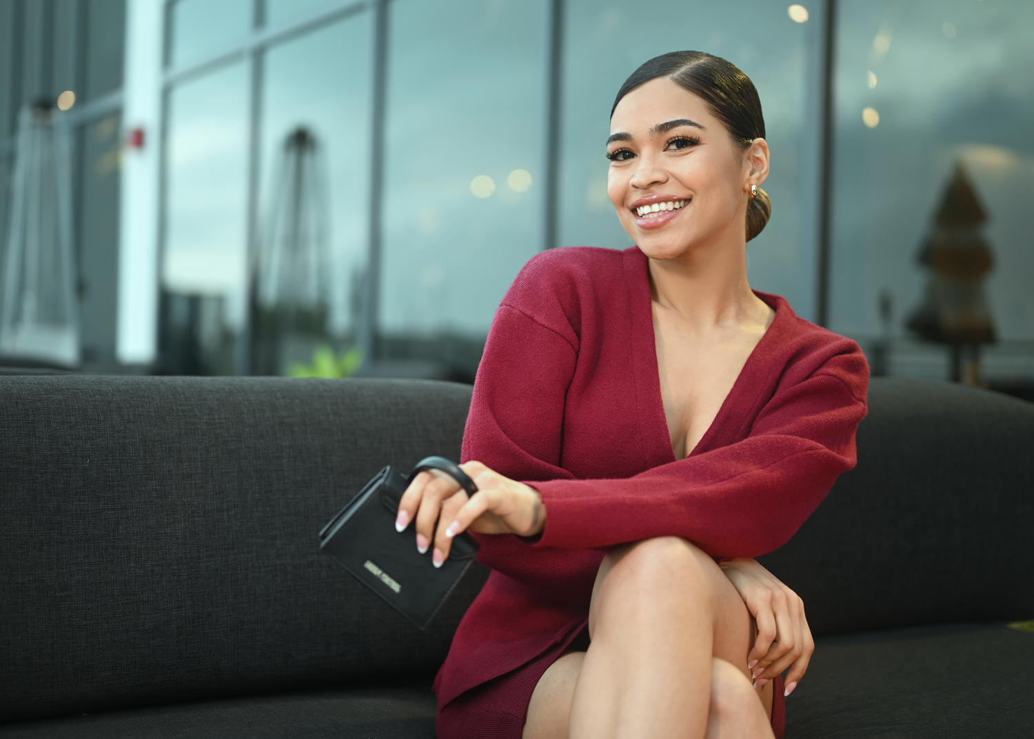 Stylish burgundy outfit captured in contemporary office space with glass windows.