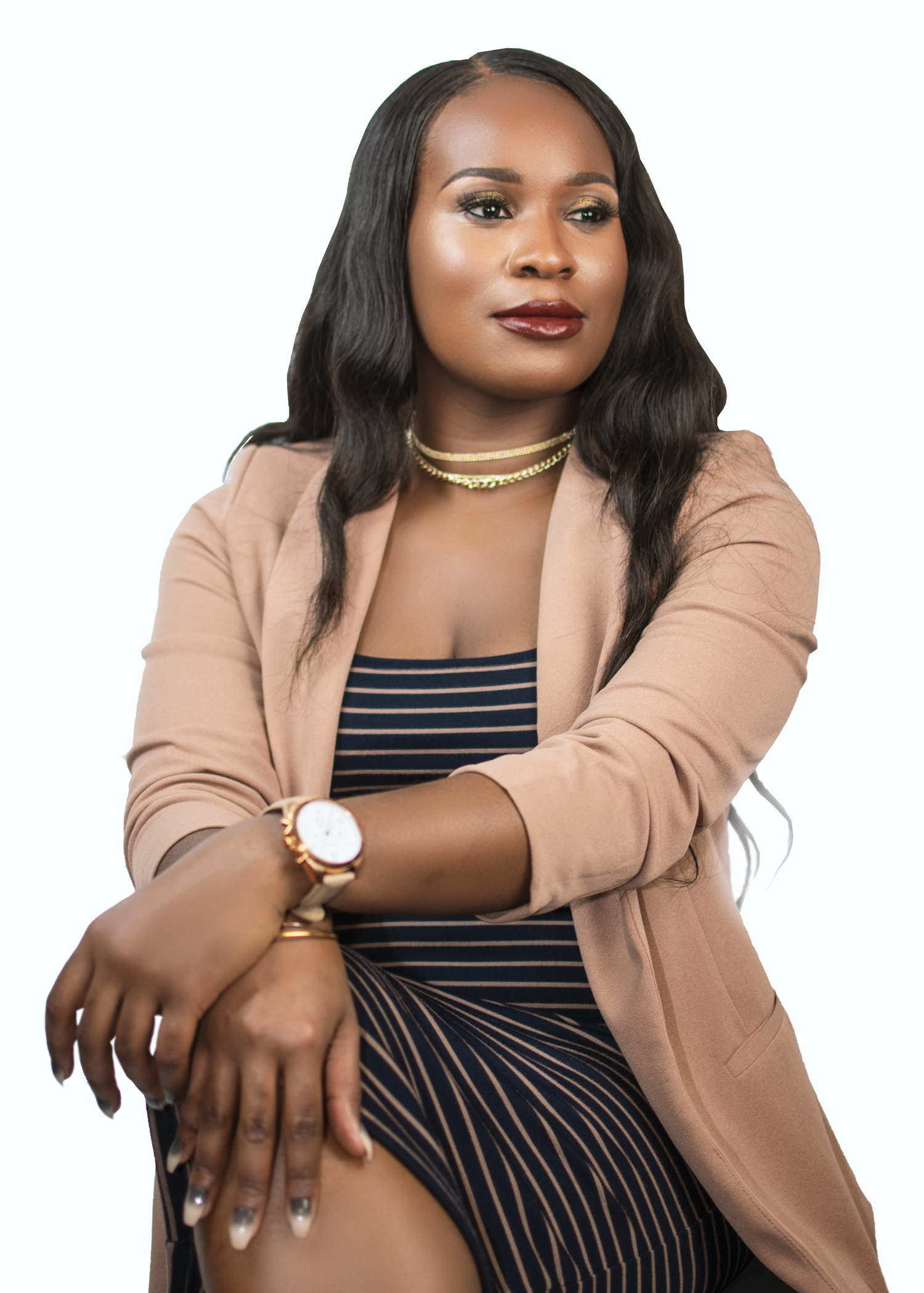 Professional woman in beige blazer and striped dress poses confidently with elegant accessories.