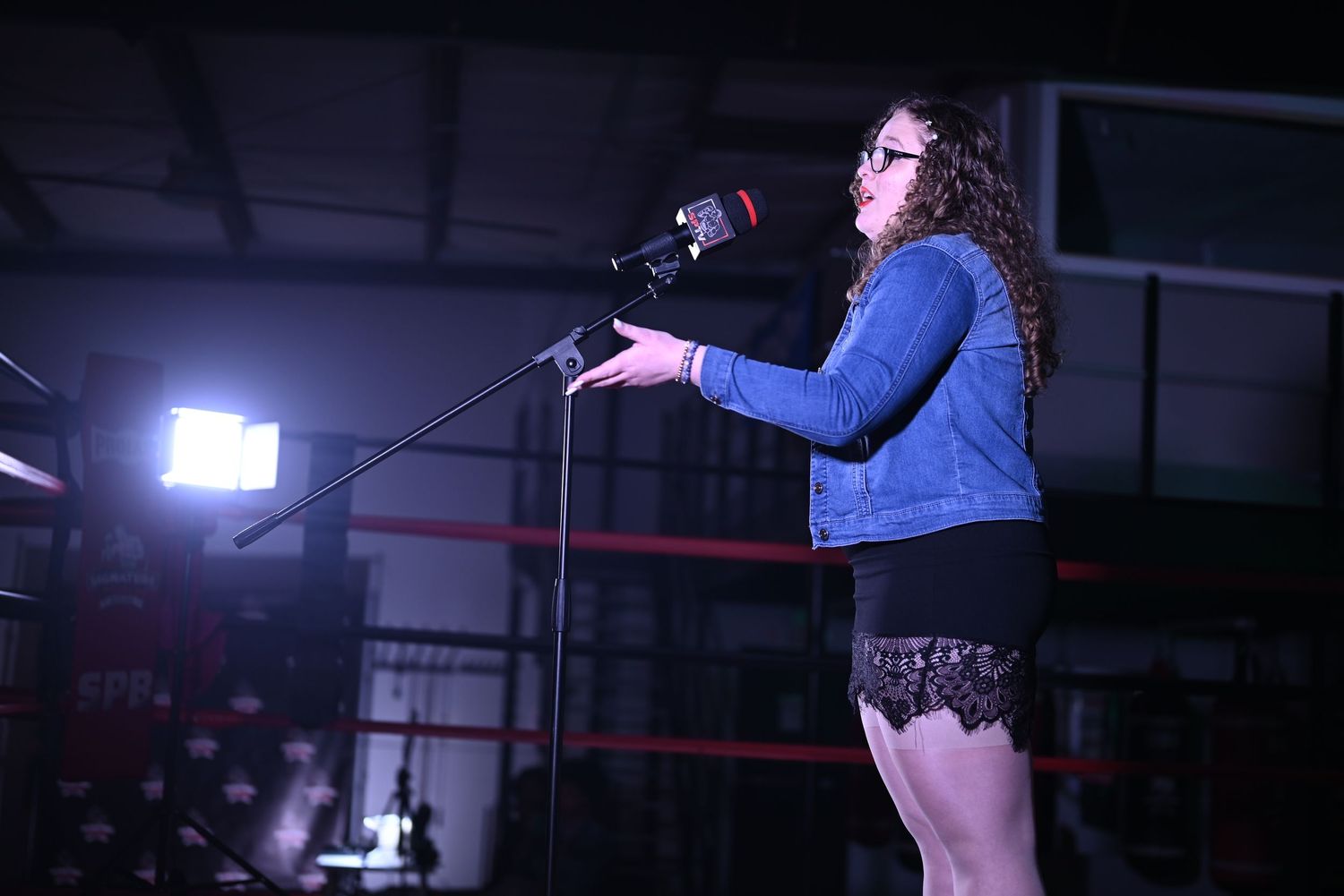 Performer on stage in dark venue with dramatic lighting effects.