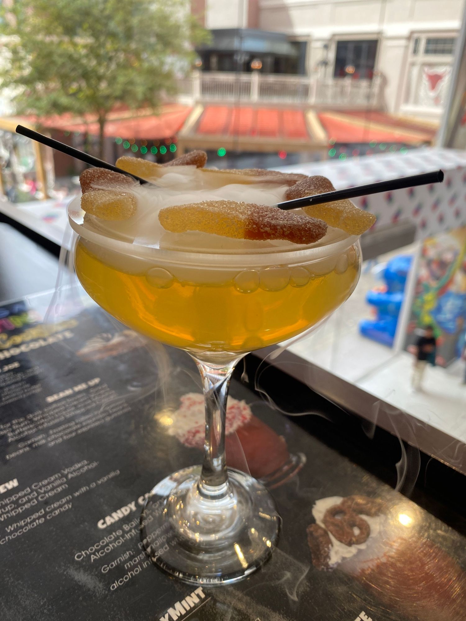Amber-colored cocktail served in a martini glass with menu in background.