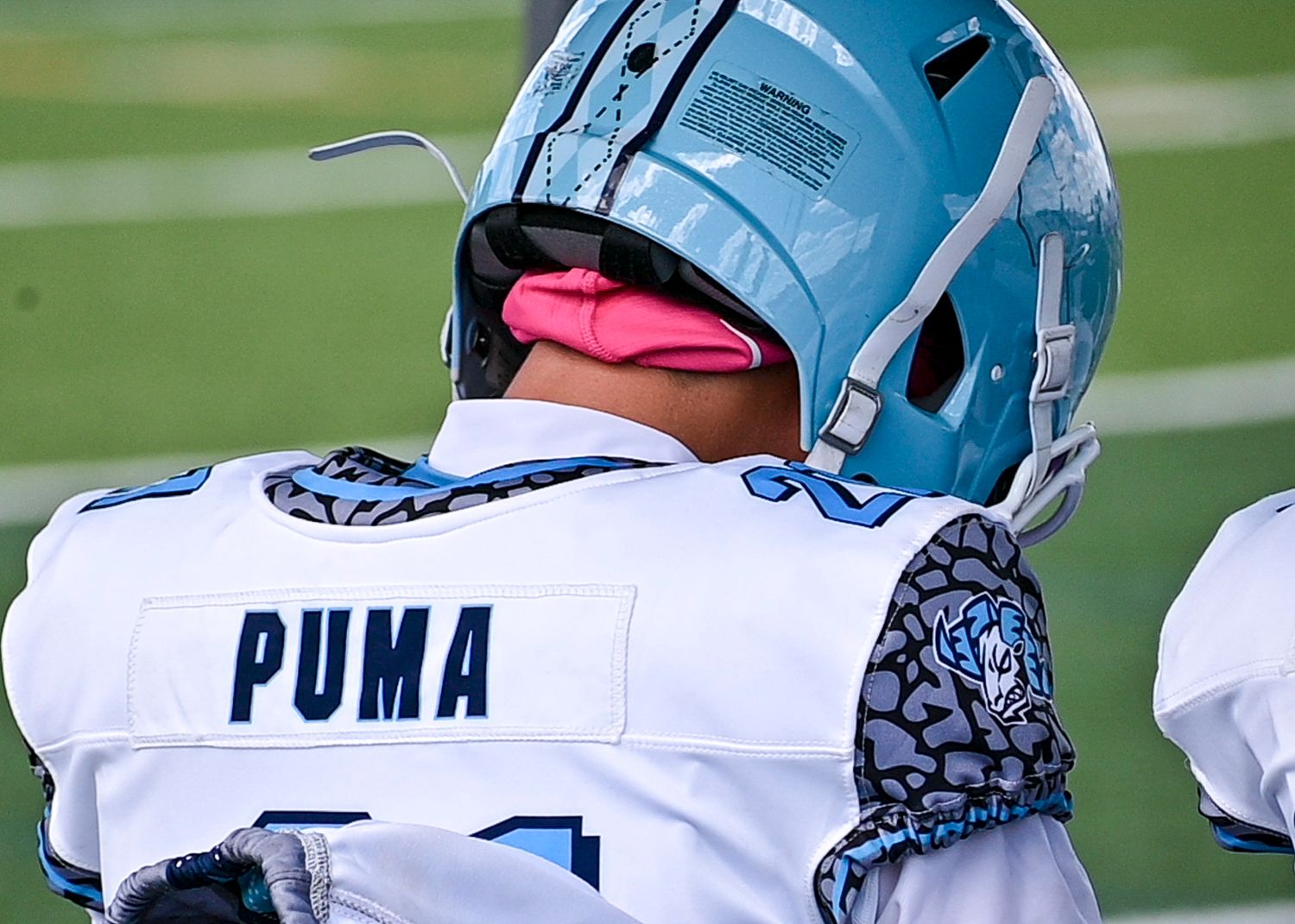 Close-up of football players' helmets and jerseys showing Puma branding.