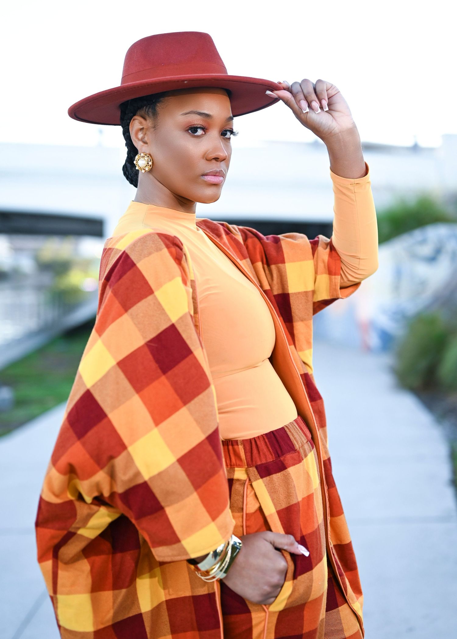 Stylish fall ensemble featuring orange and red plaid suit with matching hat.