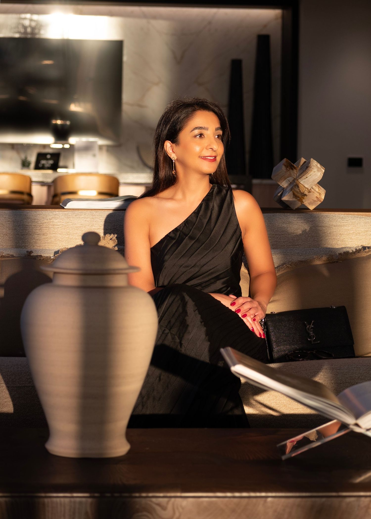 Woman in black dress posing on dark surface with dramatic lighting.
