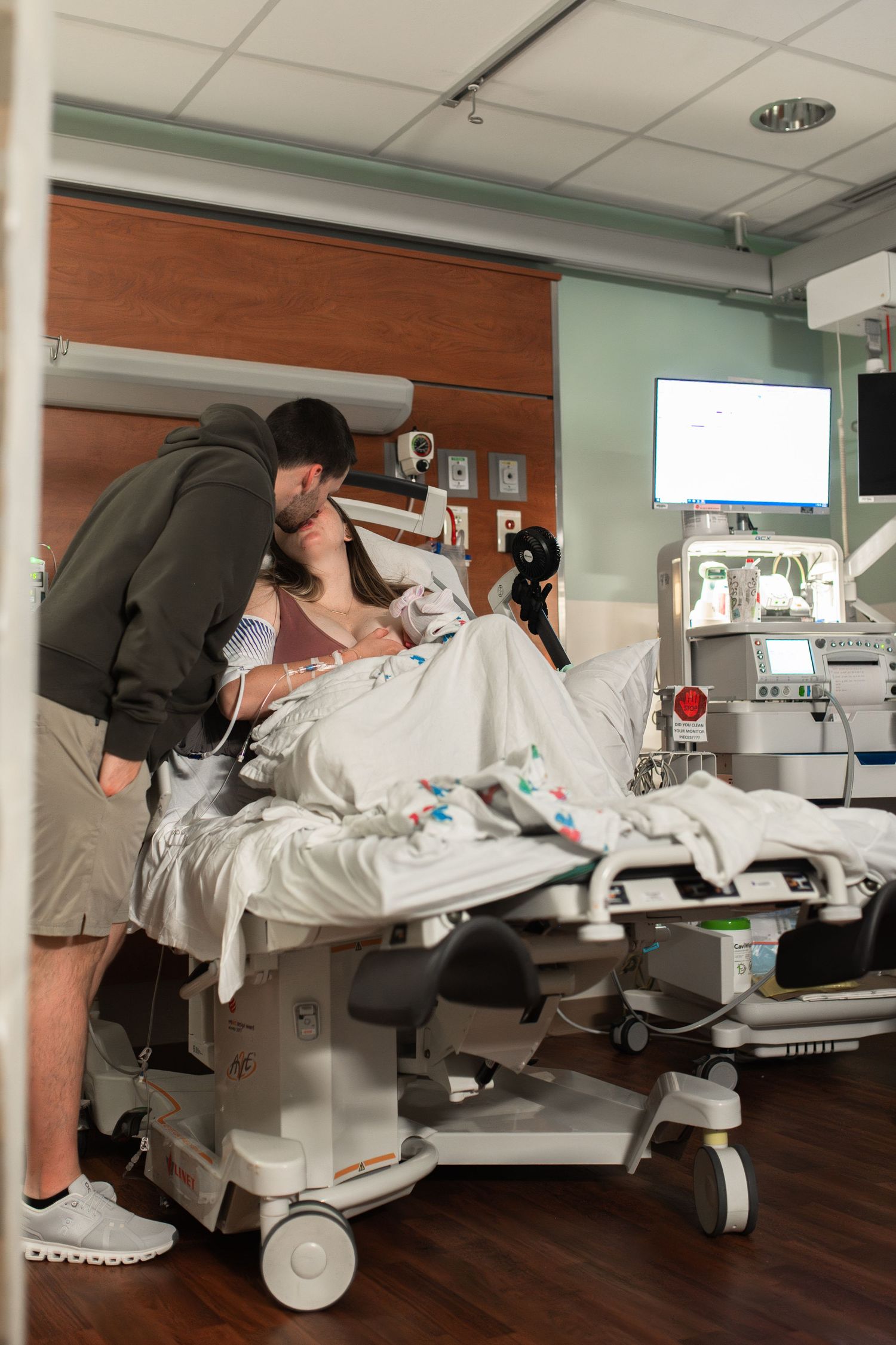 mom dad baby at birth in hospital at ECU Health Medical Center Greenville NC kissing in hospital bed