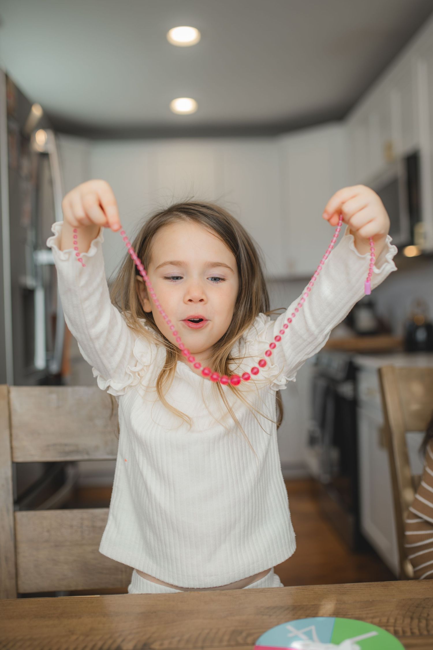 child holding up necklace for board game, greenville, nc