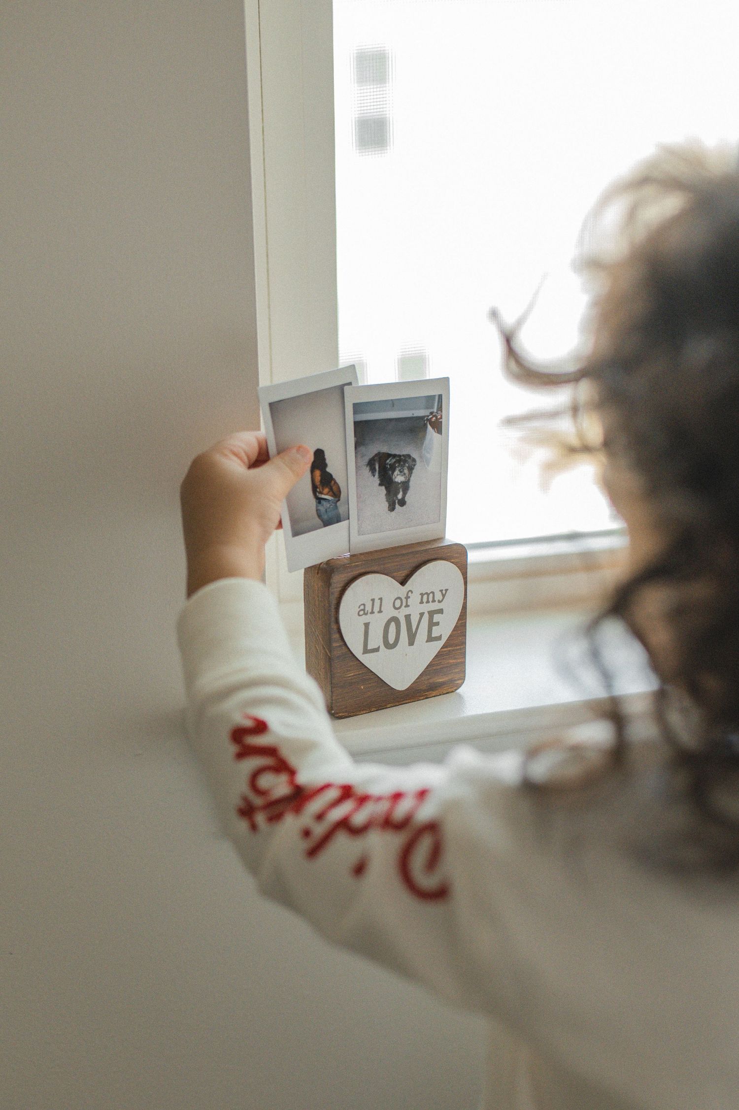 child playing near window, holding polaroid pictures
