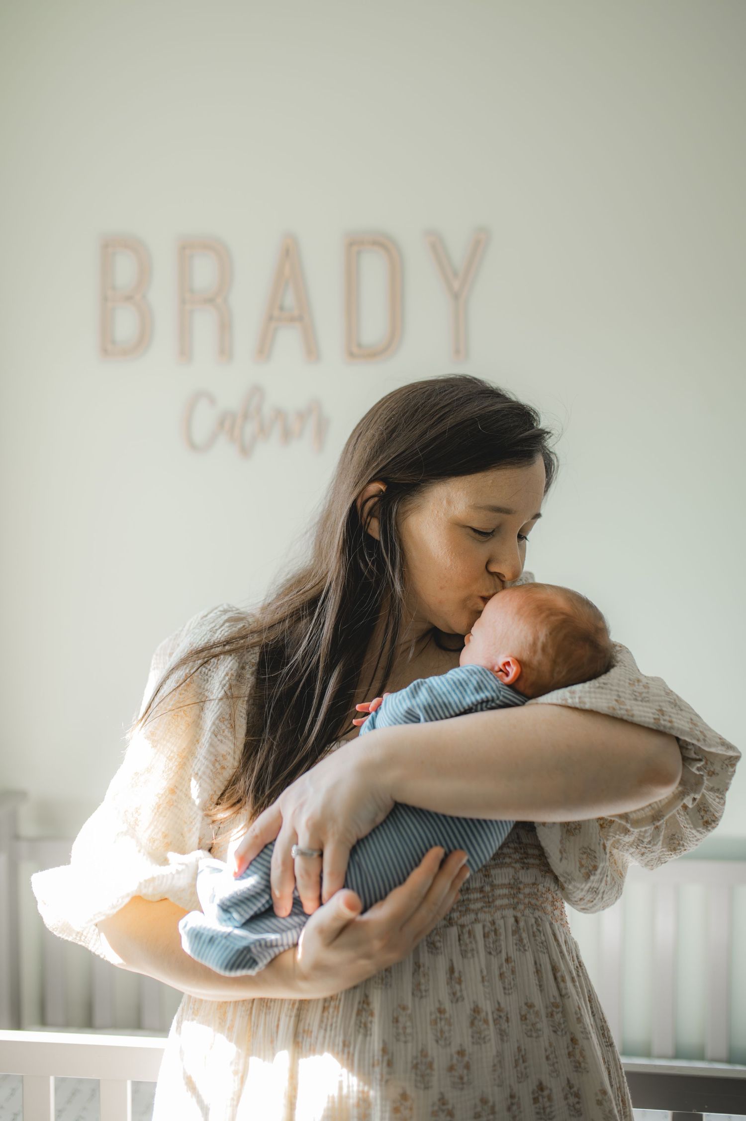 mom hold newborn baby boy, kissing forehead, cradling
