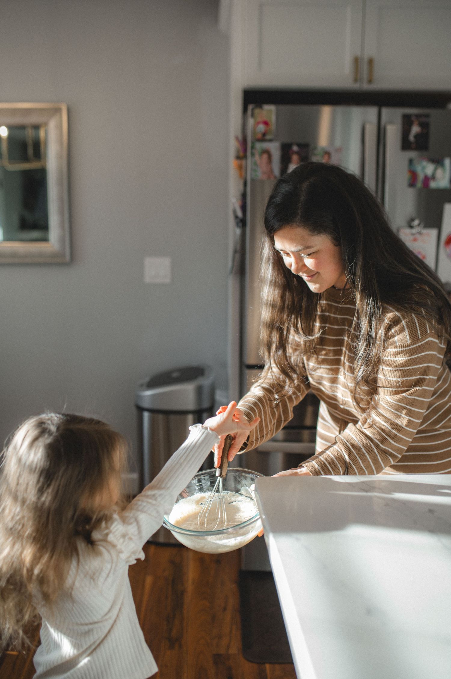 mom and daughter mixing pancake batter in glass bowl