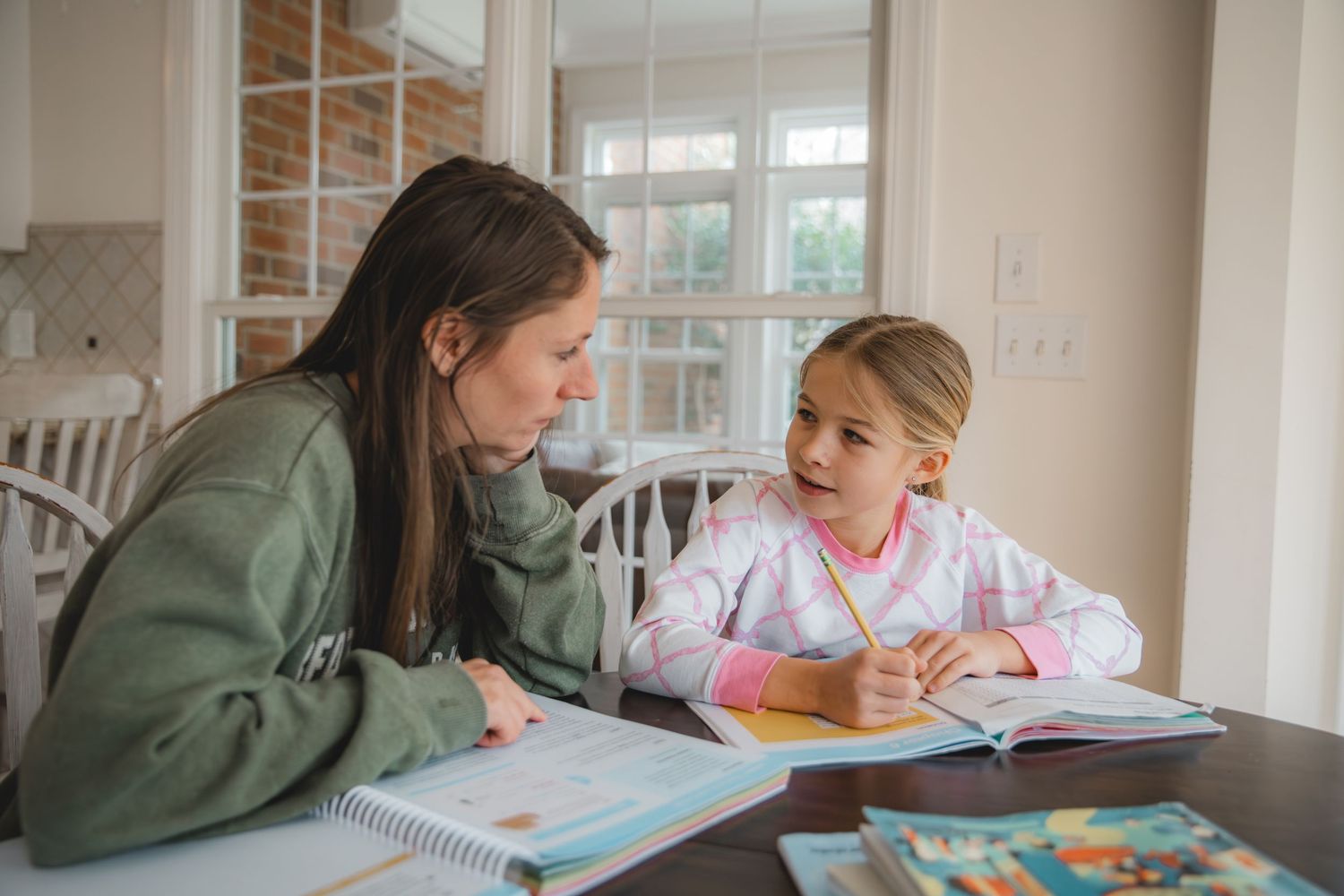 mom and daughter doing homeschool workbook, mathematics, division, looking at each other