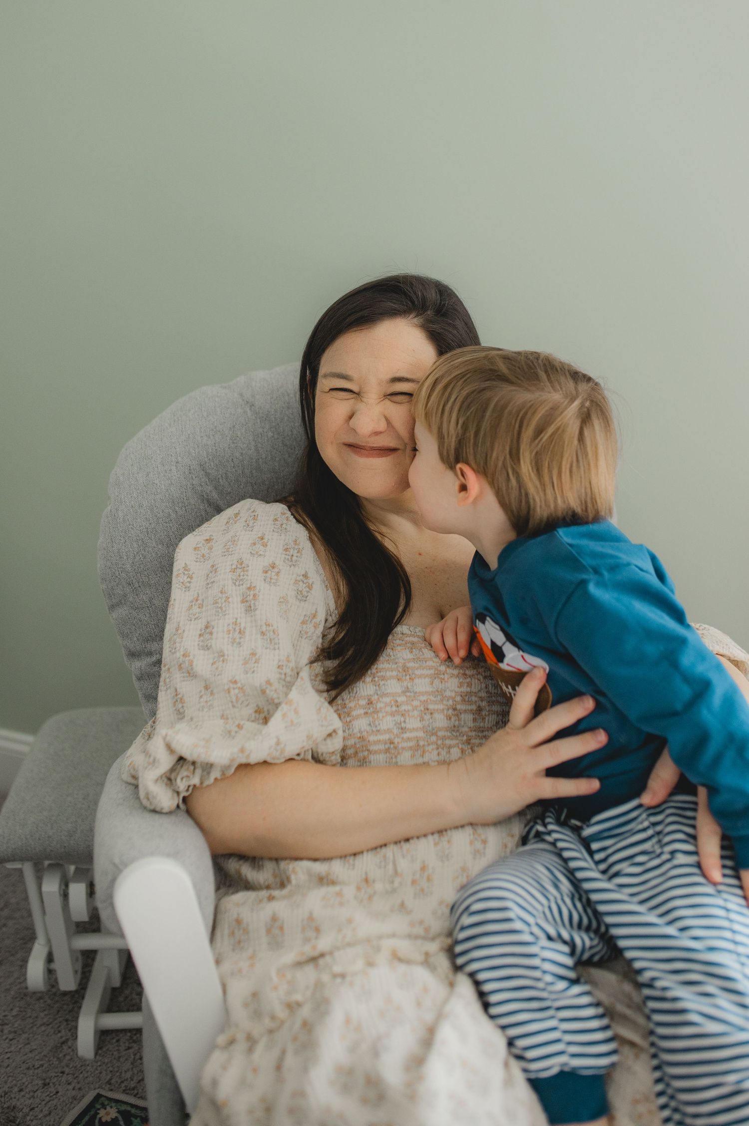 mom and son sitting in rocking chair in nursery