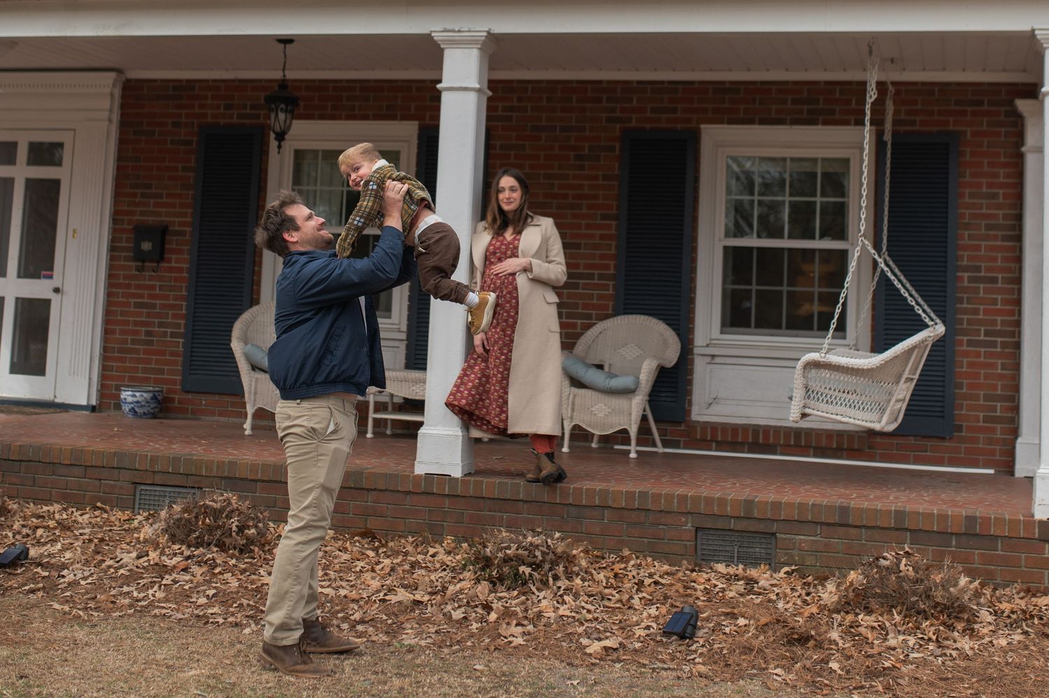 dad and son playing, mom standing on front porch leaning against column watching