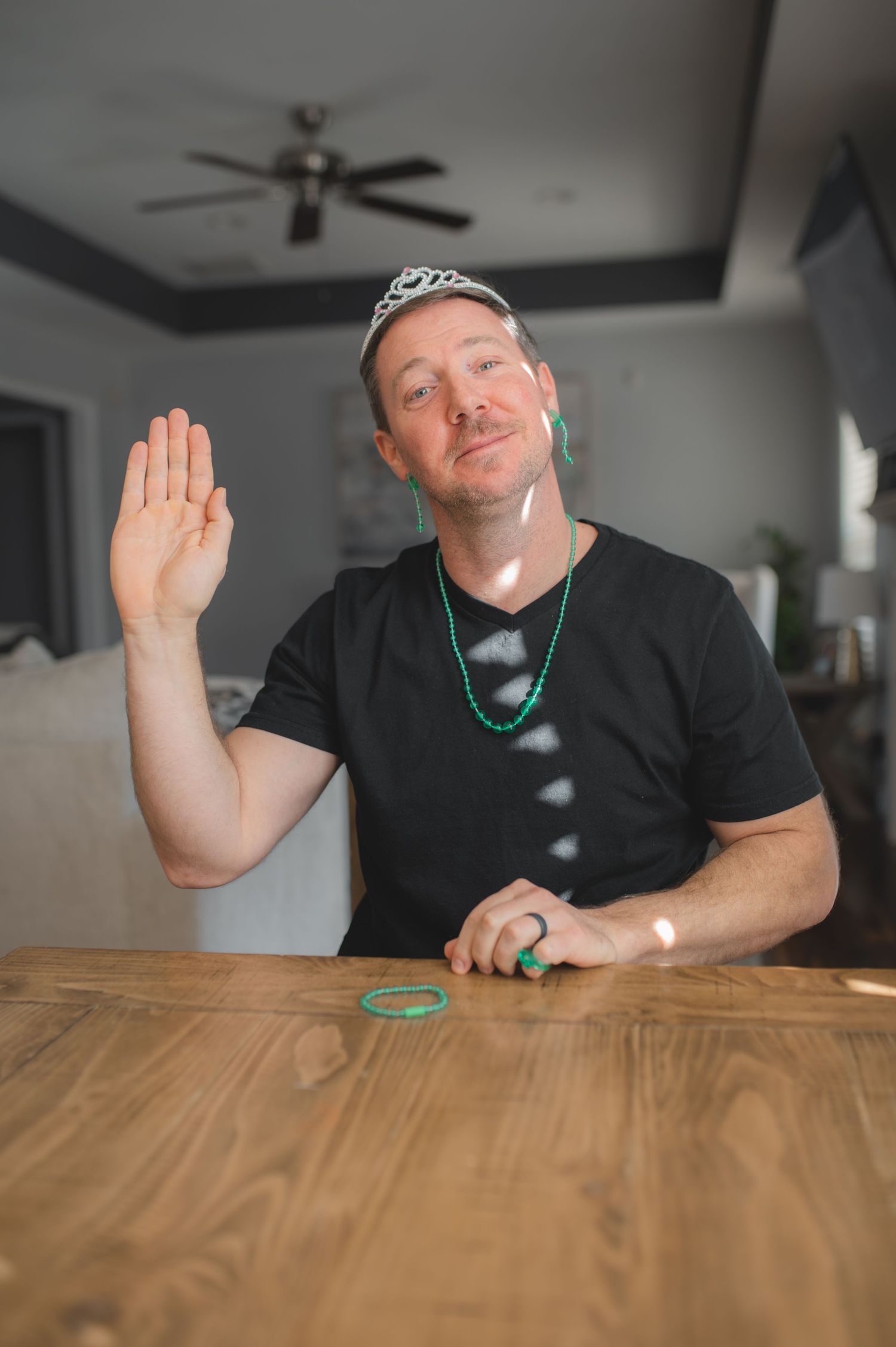 dad waving at camera, wearing earrings, necklace, bracelet, ring and tiara for board game, greenville, nc