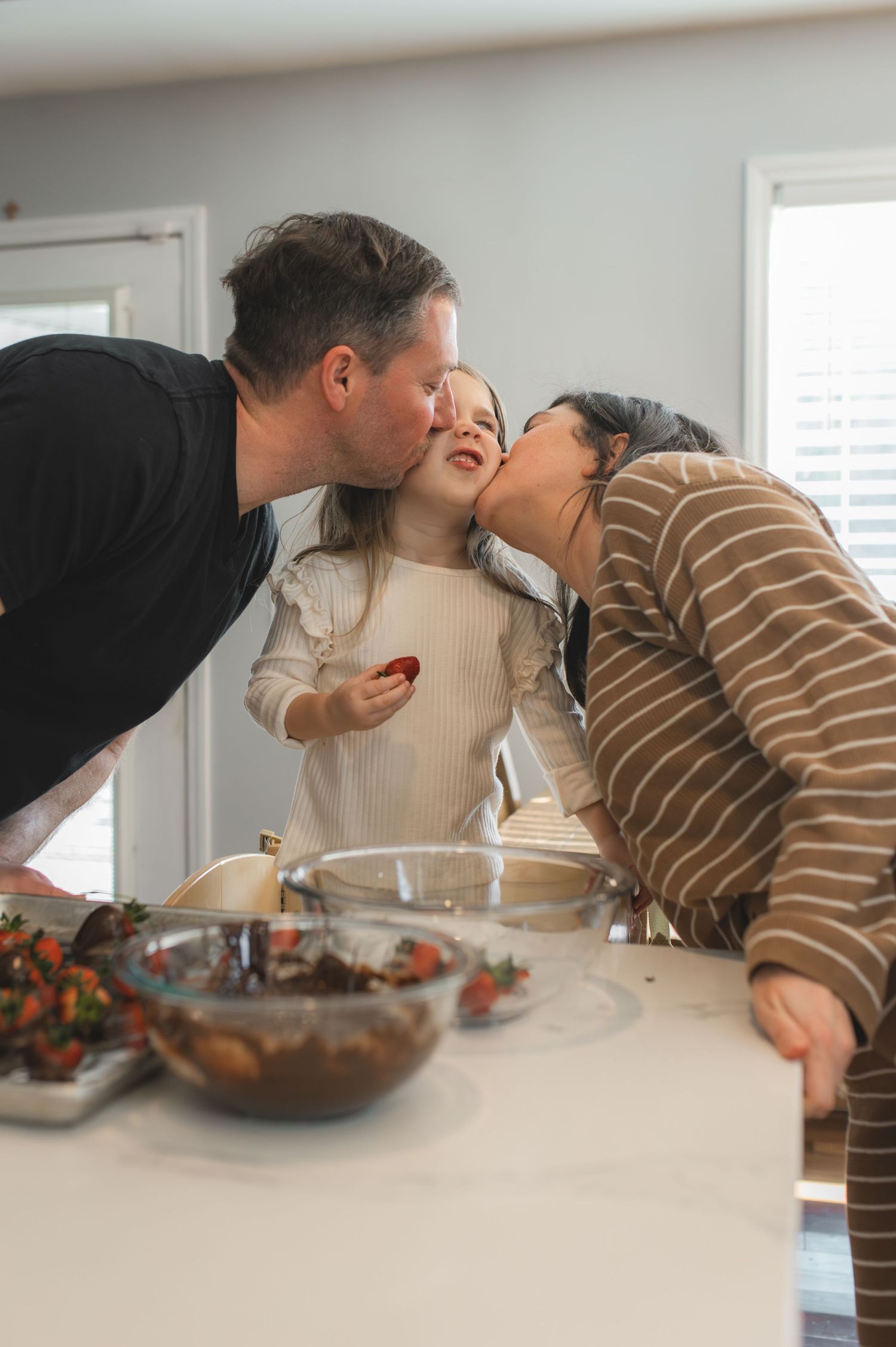 mom and dad kissing over bowl of chocolate covered strawberries, greenville, nc