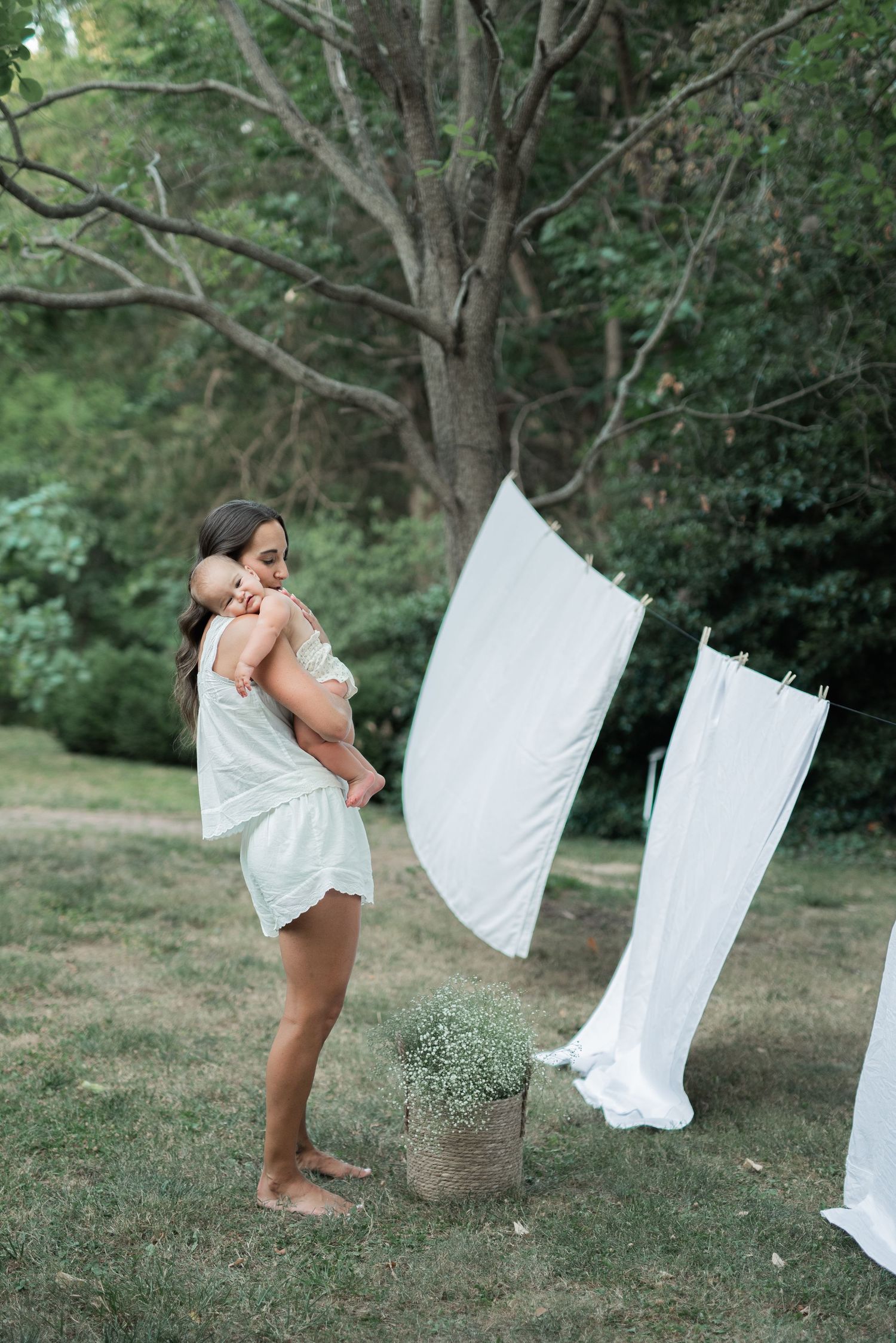 mom and baby outside standing by on white sheet on clothesline hugging