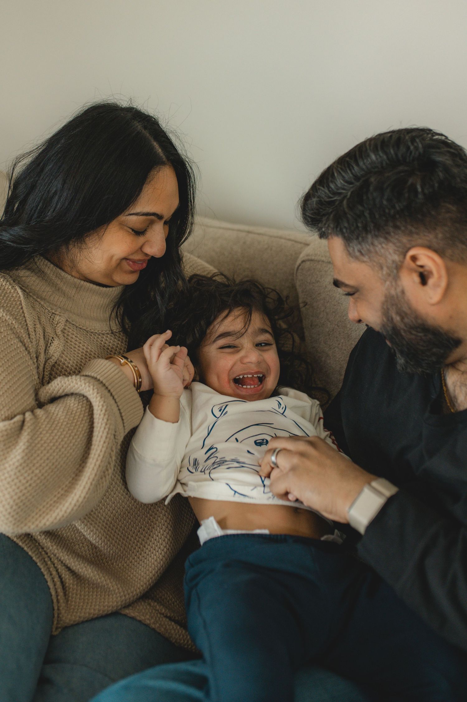 mom dad and son on couch, holding hands, playing, laughing, smiling, hugging