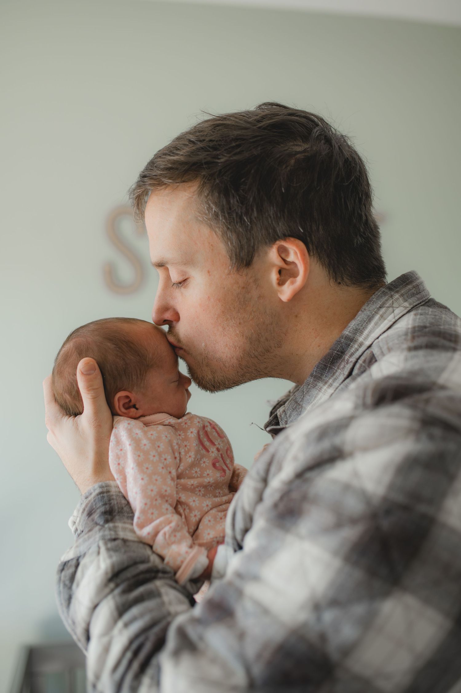 dad holding newborn baby girl, kissing forehead