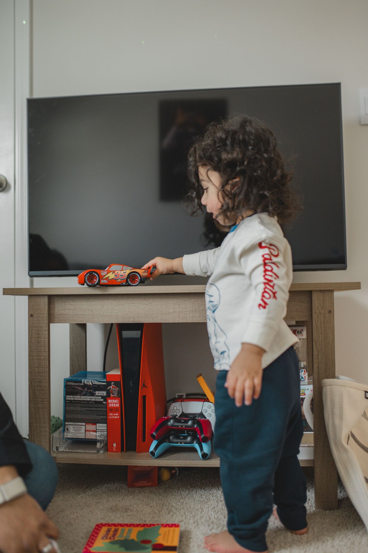 child play with lightning mcqueen race car in front of tv