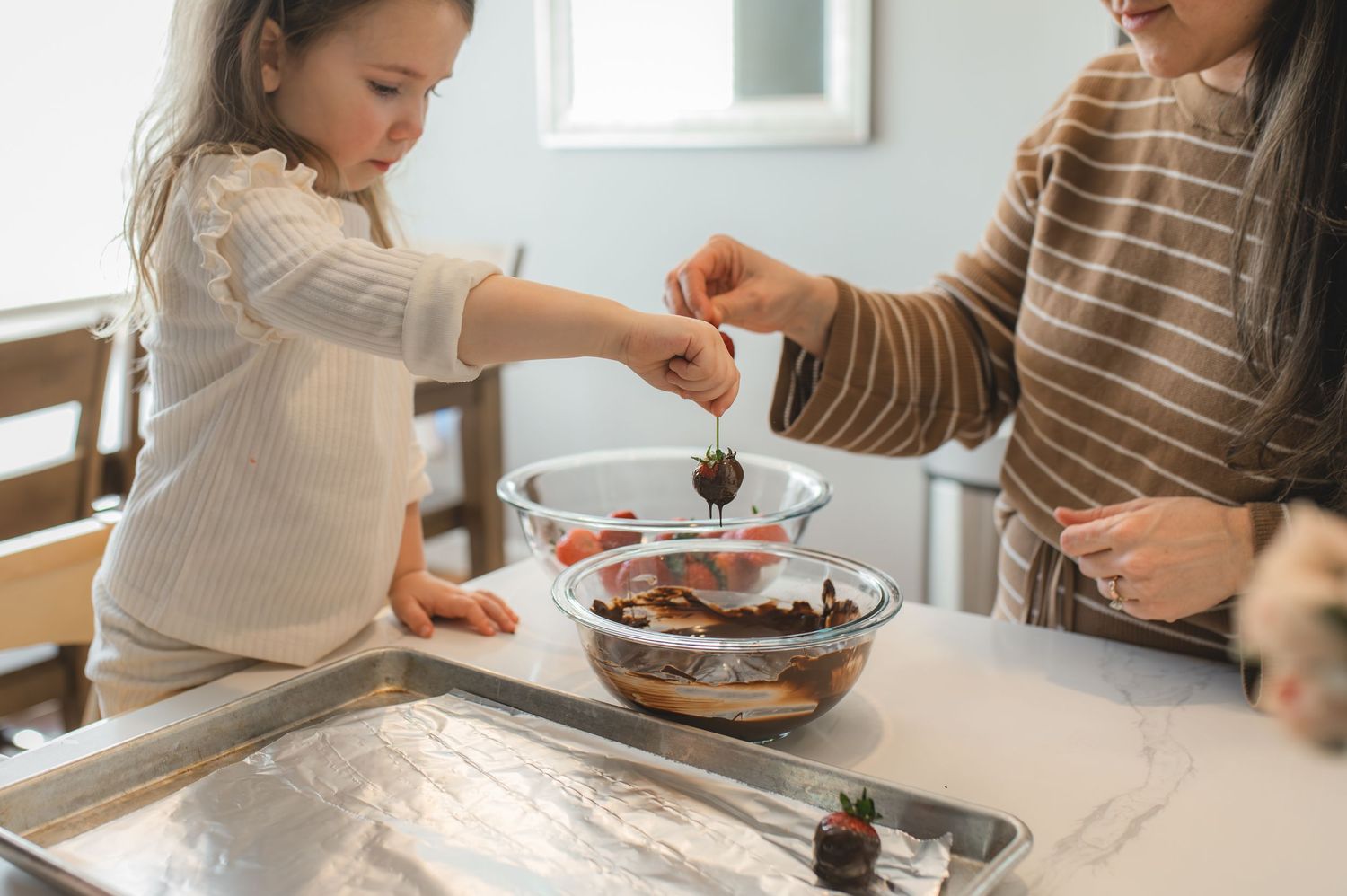 mom and child with baking tray and bowl of strawberries and chocolate, greenville, nc