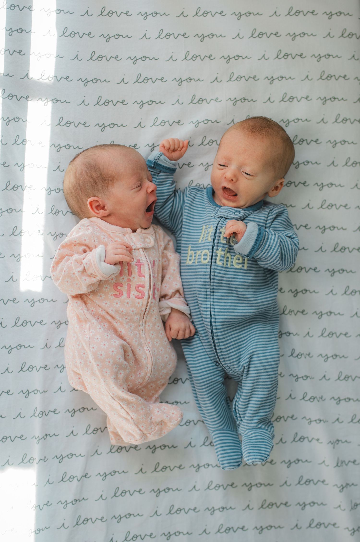 newborn twin boy and girl laying beside each other yawning, little brother, little sister, pink, blue