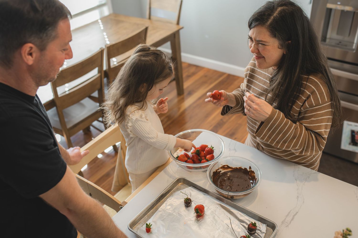 mom dad and child with baking tray and bowl of strawberries and chocolate, greenville, nc