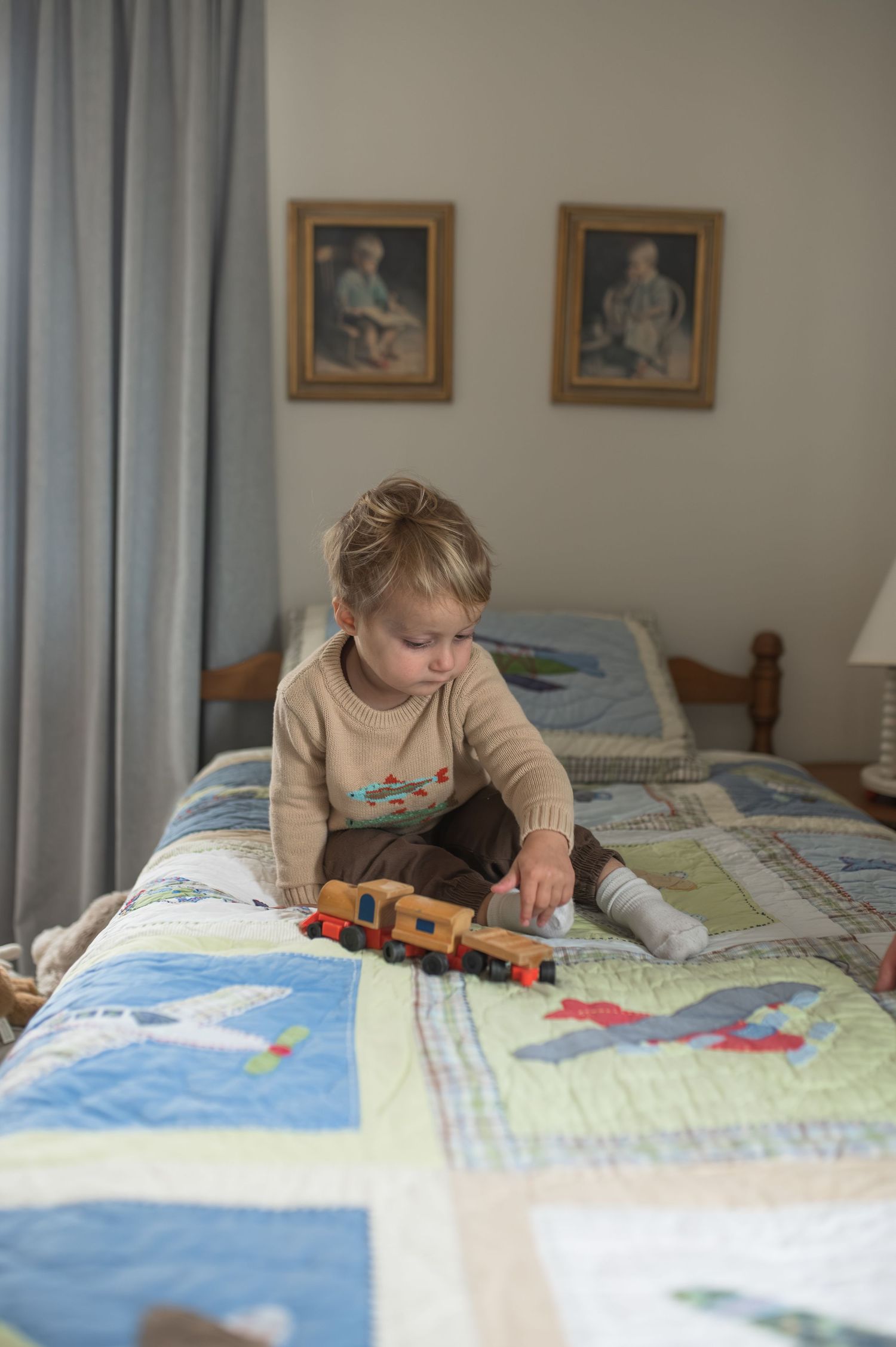 child playing on bed with wooden toys
