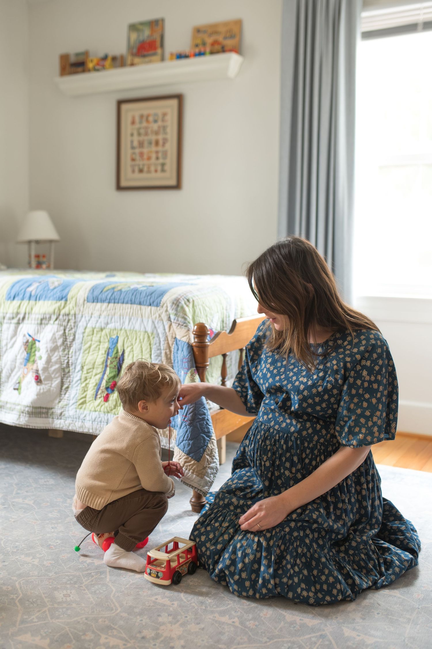 mom and toddler sitting on floor playing with toys. pregnant mama holding belly smiling. at home documentary family maternity session