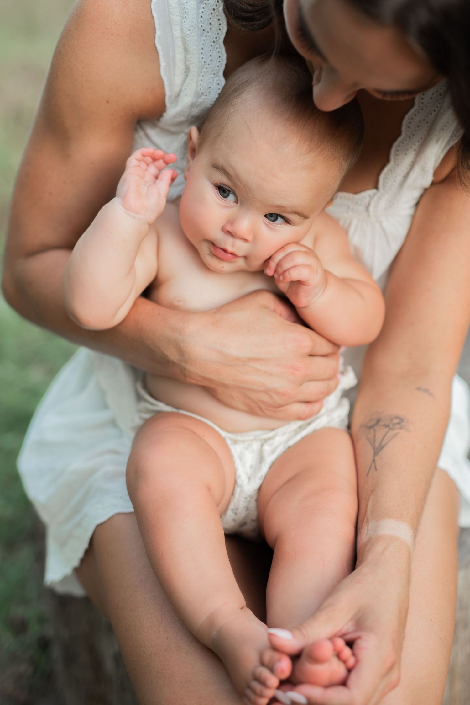 mom holding baby and tickling feet tattoo on arm.