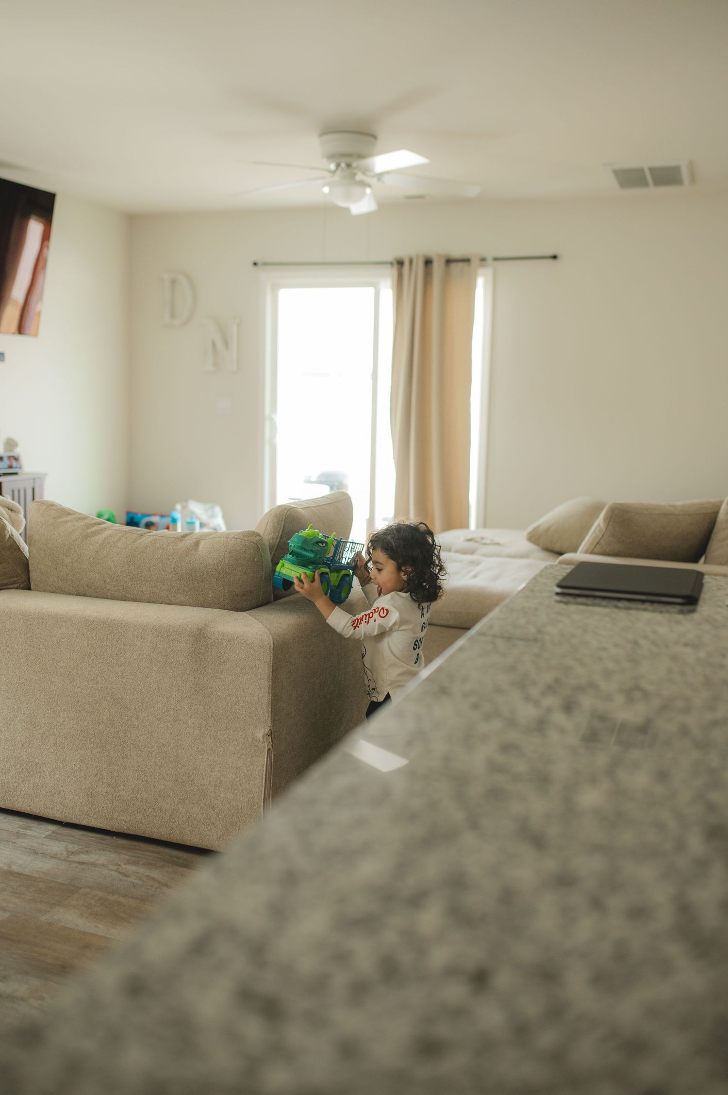 child playing with truck on back of couch