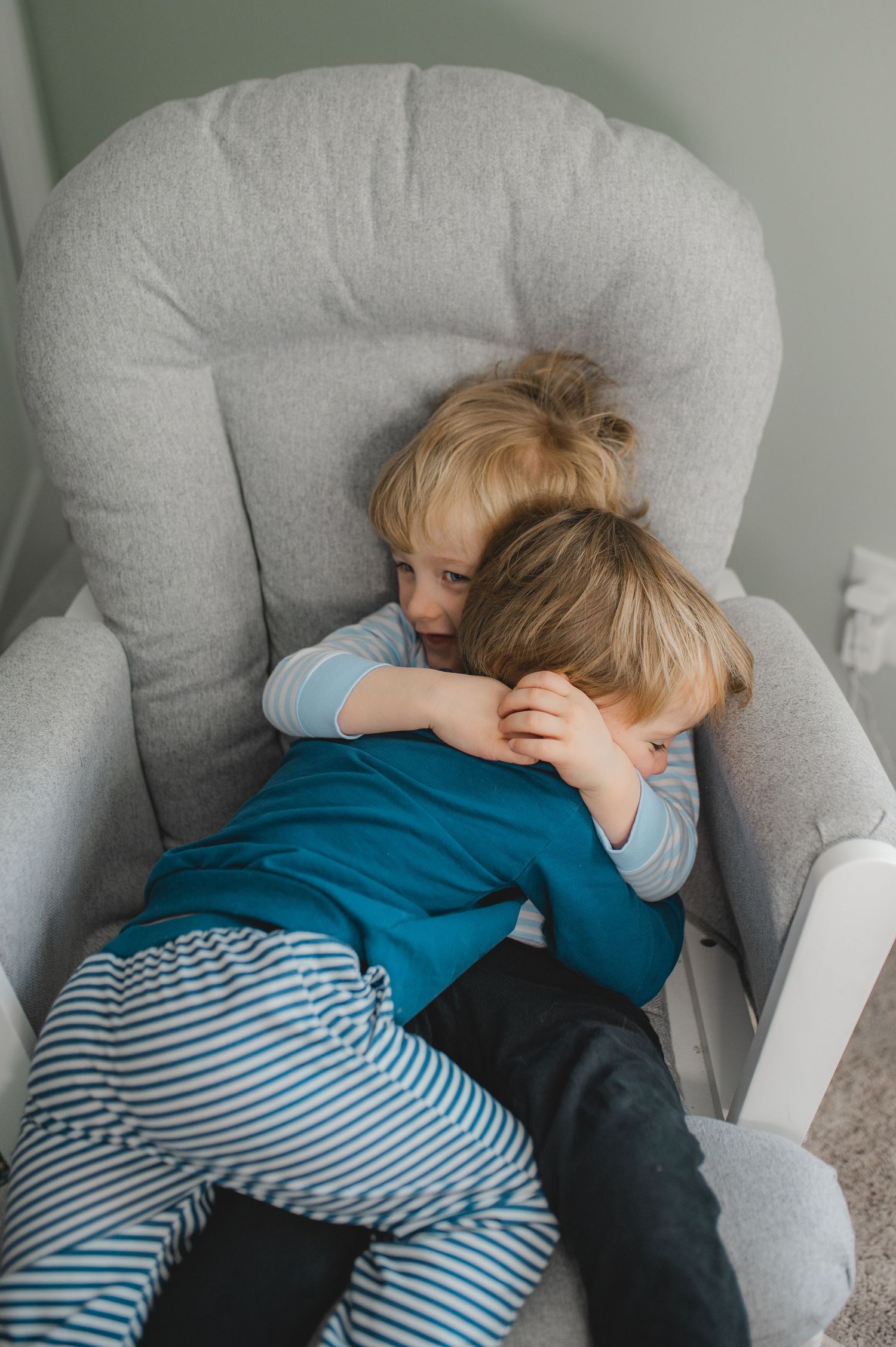 twin boys hugging in rocking chair in nursery