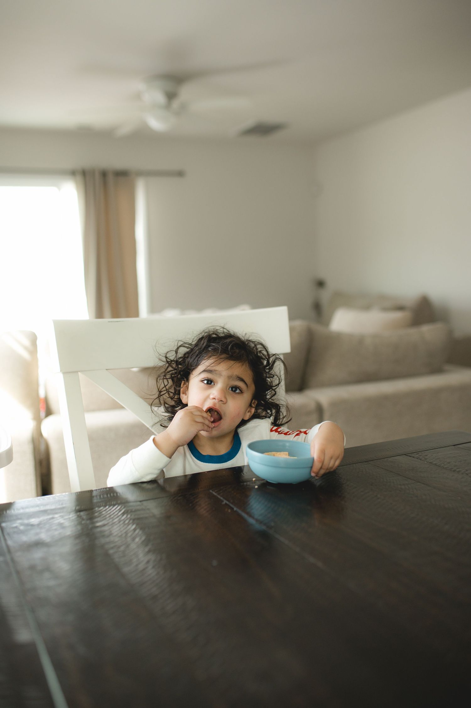 child eating a snack at table with blue bowl and bluey straw cup