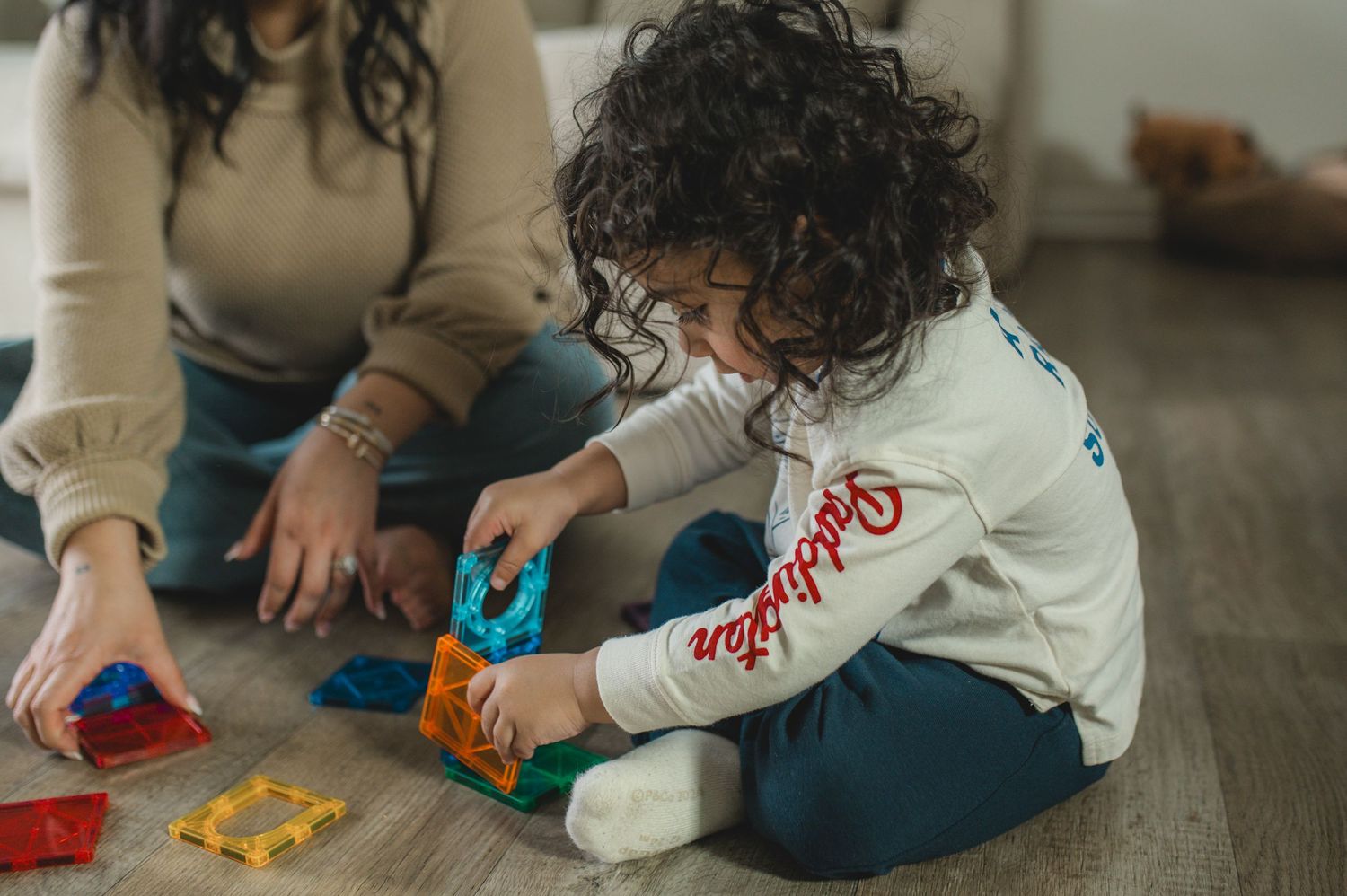 child and mom playing with magna-tiles on floor during at-home family documentary photography session