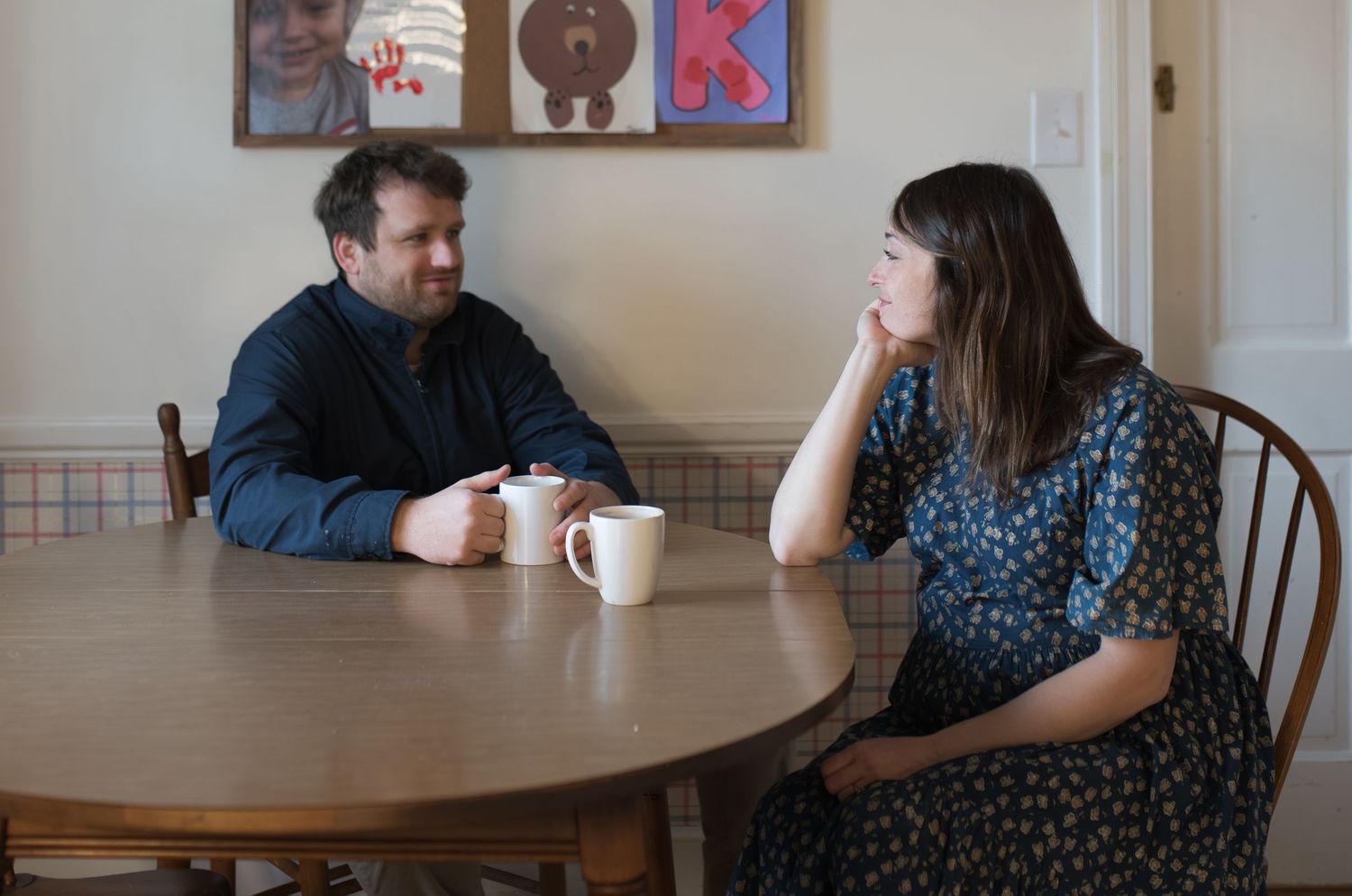 mom and dad drinking coffee, sitting at kitchen table. pregnant, maternity, at home family session