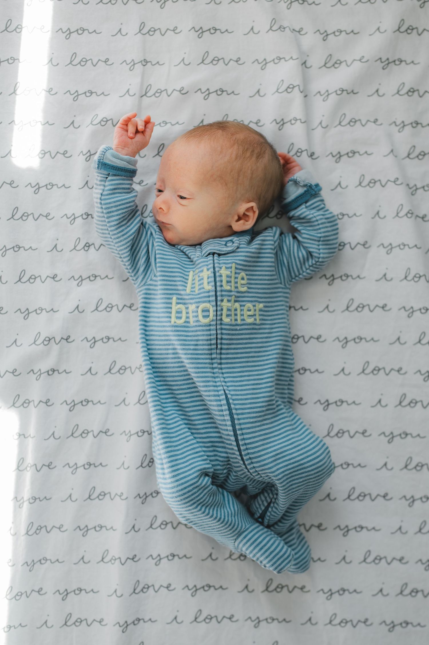 newborn twin boy laying in crib, little brother, blue, stretching