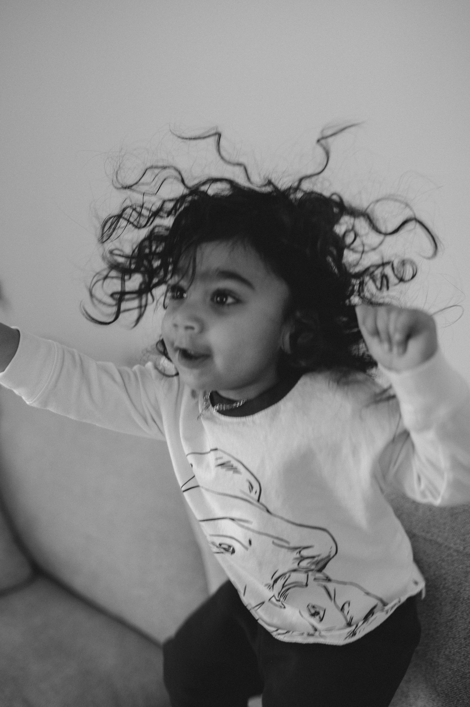 child jumping on couch, curly hair going all over the place