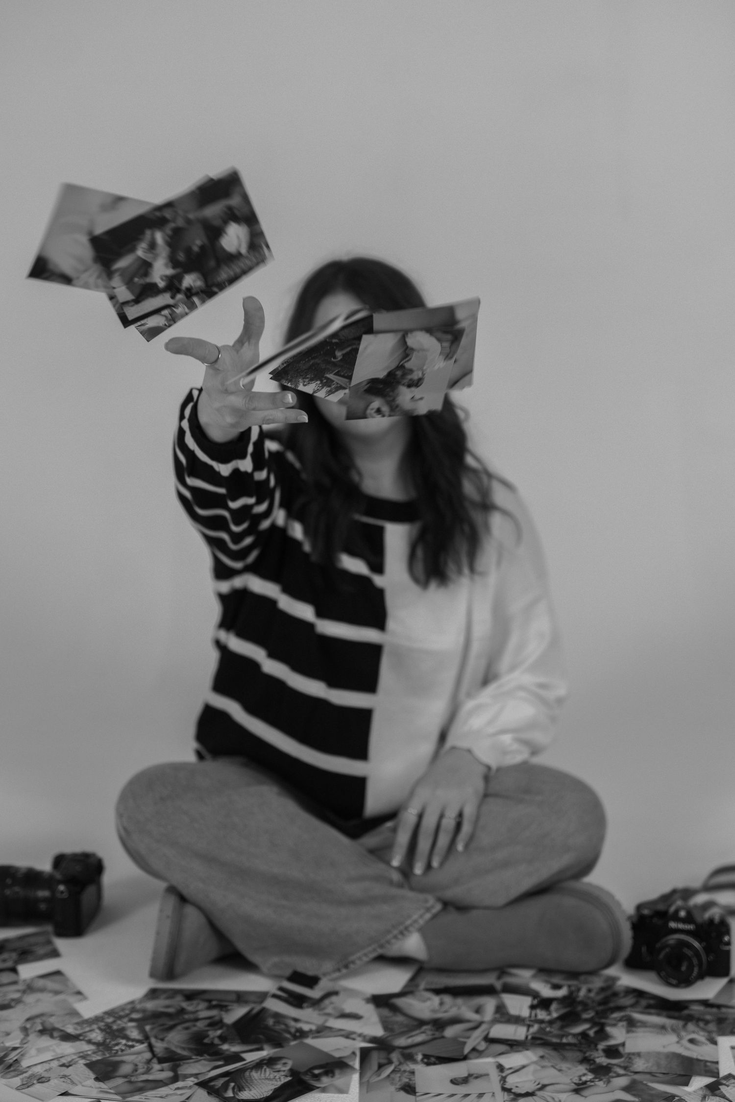 black and white photos. hand throwing printed pictures toward camera. black and white striped sweater.