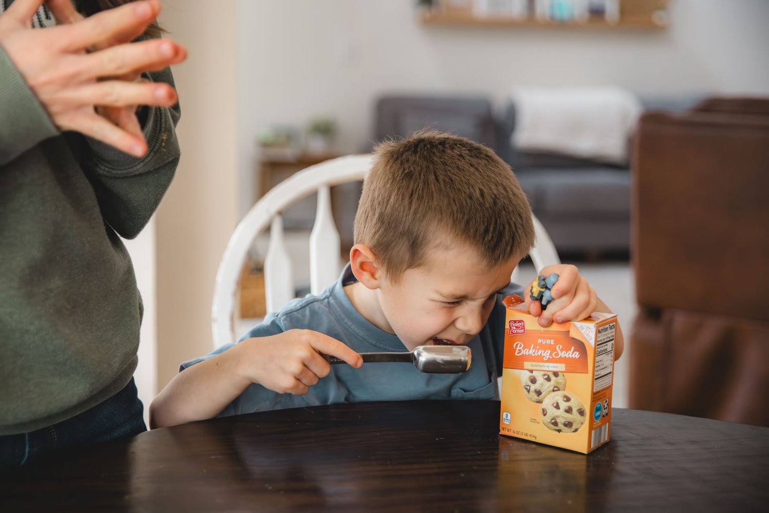 child scooping baking soda into a tablespoon, looking into box