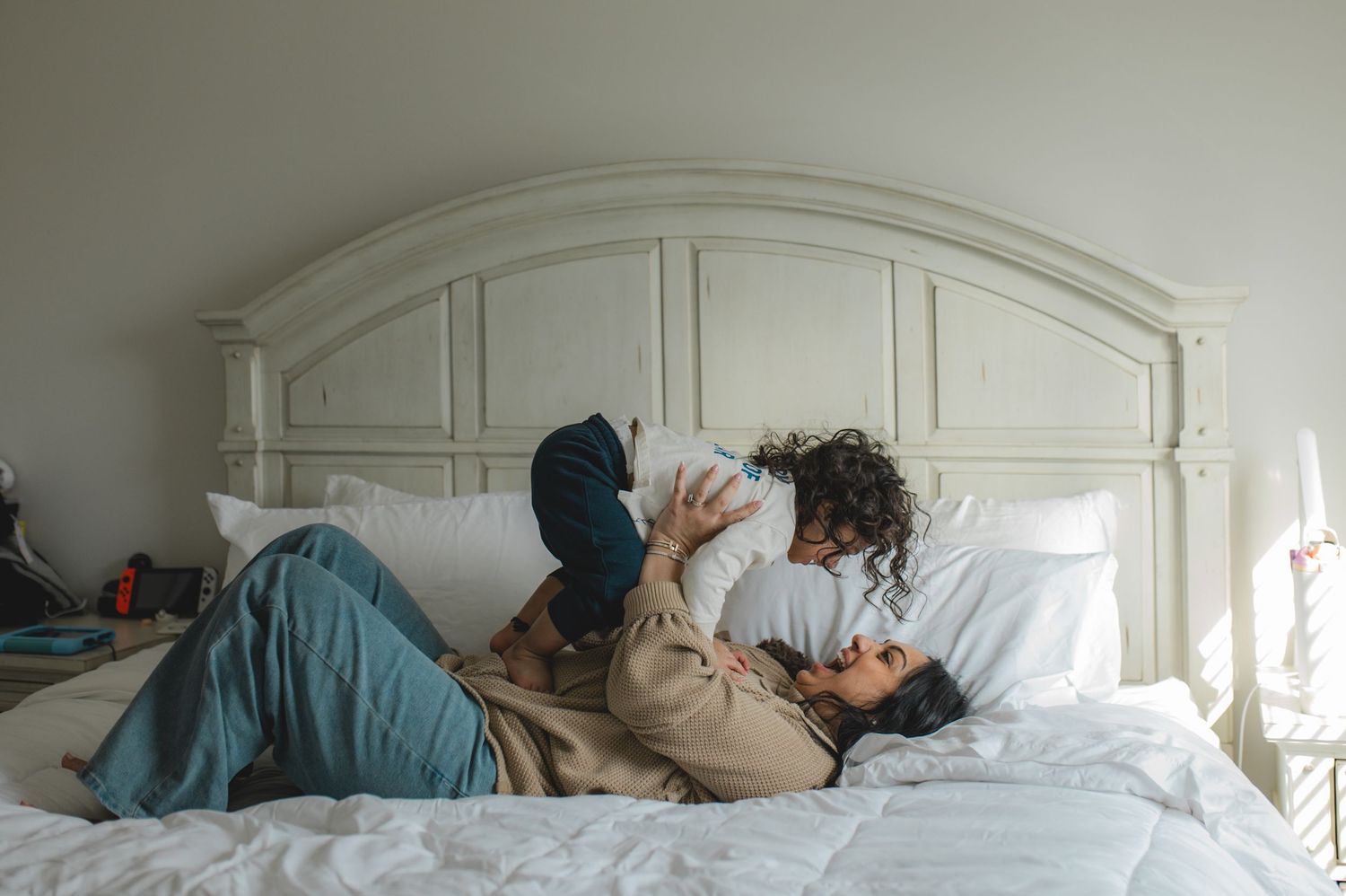 mom and son laying on bed, holding hands, playing, laughing, smiling